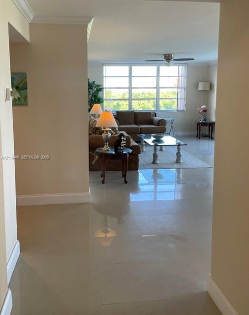 Neutral tile flooring, large multi-pane windows, and a ceiling fan