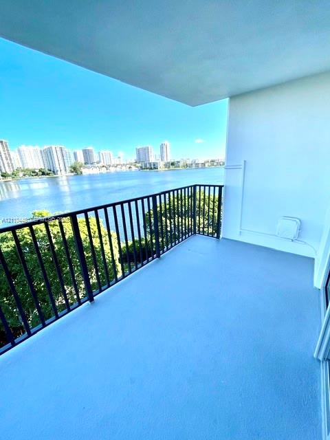 Covered balcony featuring concrete flooring, black metal railing, and water frontage