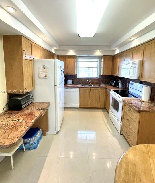 Kitchen featuring wood cabinetry, stone countertops, tiled flooring, recessed ceiling lighting, and a double-basin sink