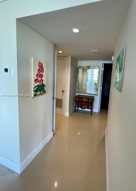 Hallway featuring polished tile flooring, recessed ceiling lighting, and a neutral color palette