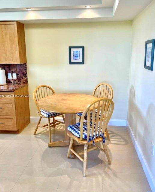 Natural wood cabinetry, stone countertops, large-format tile flooring, and recessed ceiling lighting