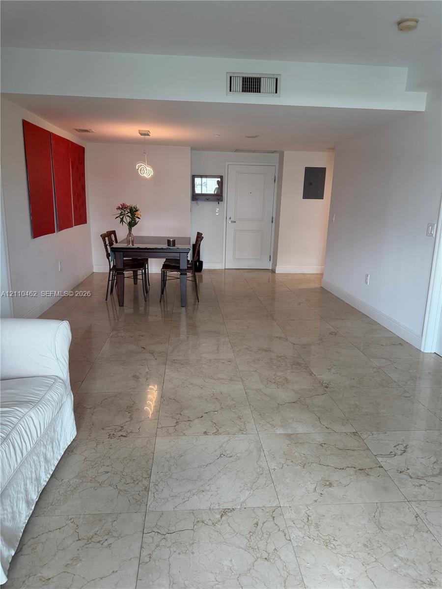 Large-format polished stone flooring with neutral veining and a single pendant light fixture Large-format polished stone flooring with neutral veining and a single pendant light fixture