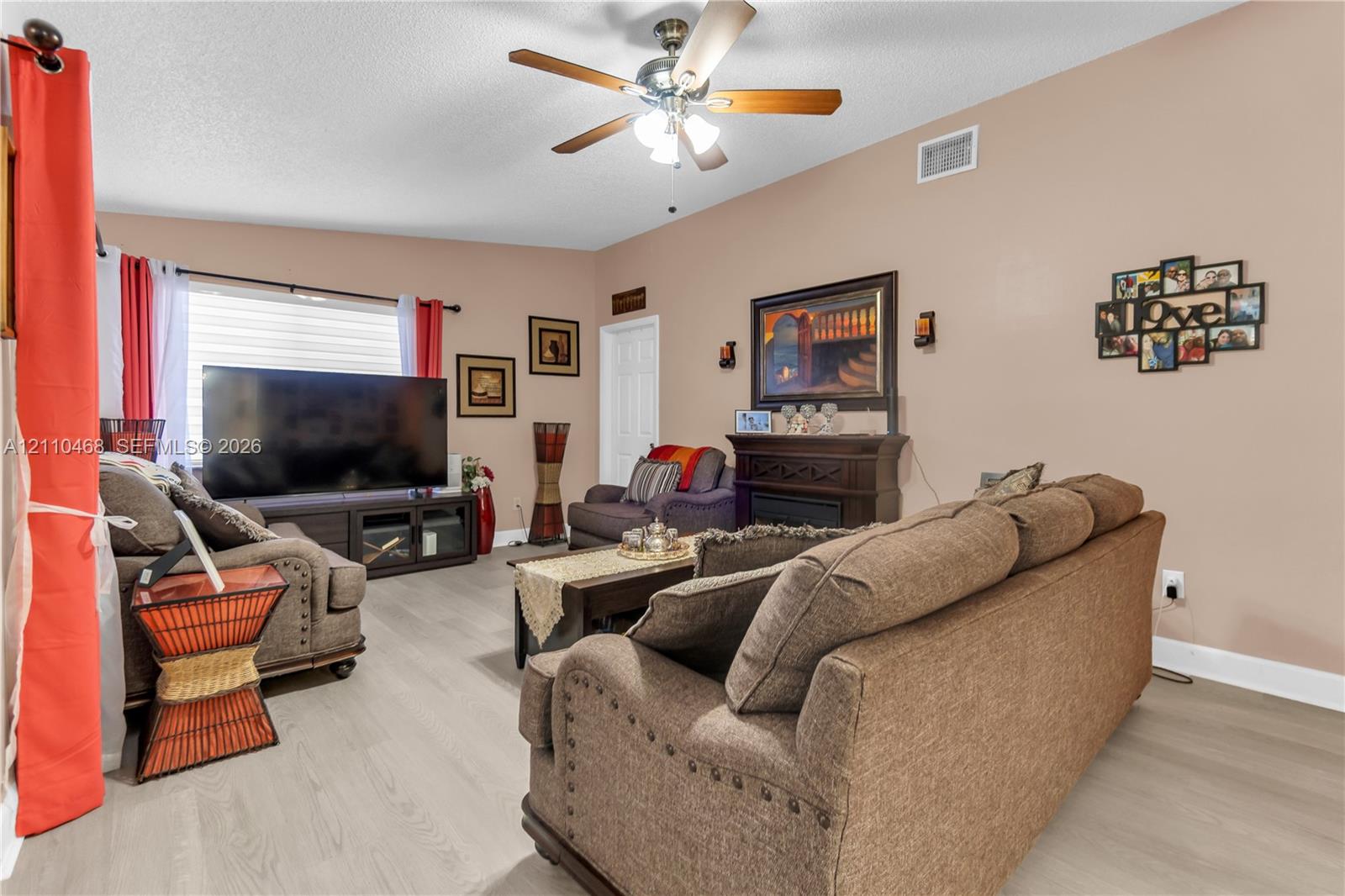 Living area featuring wood-finish flooring, a ceiling fan with integrated lighting, and a built-in decorative mantle Living area featuring wood-finish flooring, a ceiling fan with integrated lighting, and a built-in decorative mantle