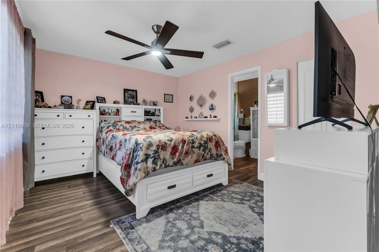 Wood-finish flooring, ceiling fan with integrated lighting, and a built-in wall shelf
