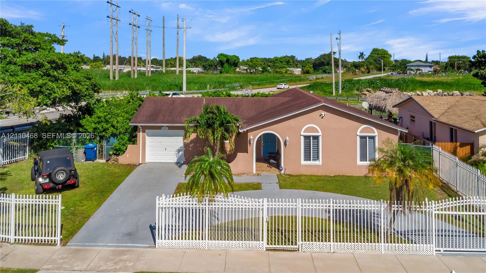 Single-story residence featuring a stucco exterior, arched window detailing, an attached garage, and full-property white picket-style perimeter fencing Single-story residence featuring a stucco exterior, arched window detailing, an attached garage, and full-property white picket-style perimeter fencing