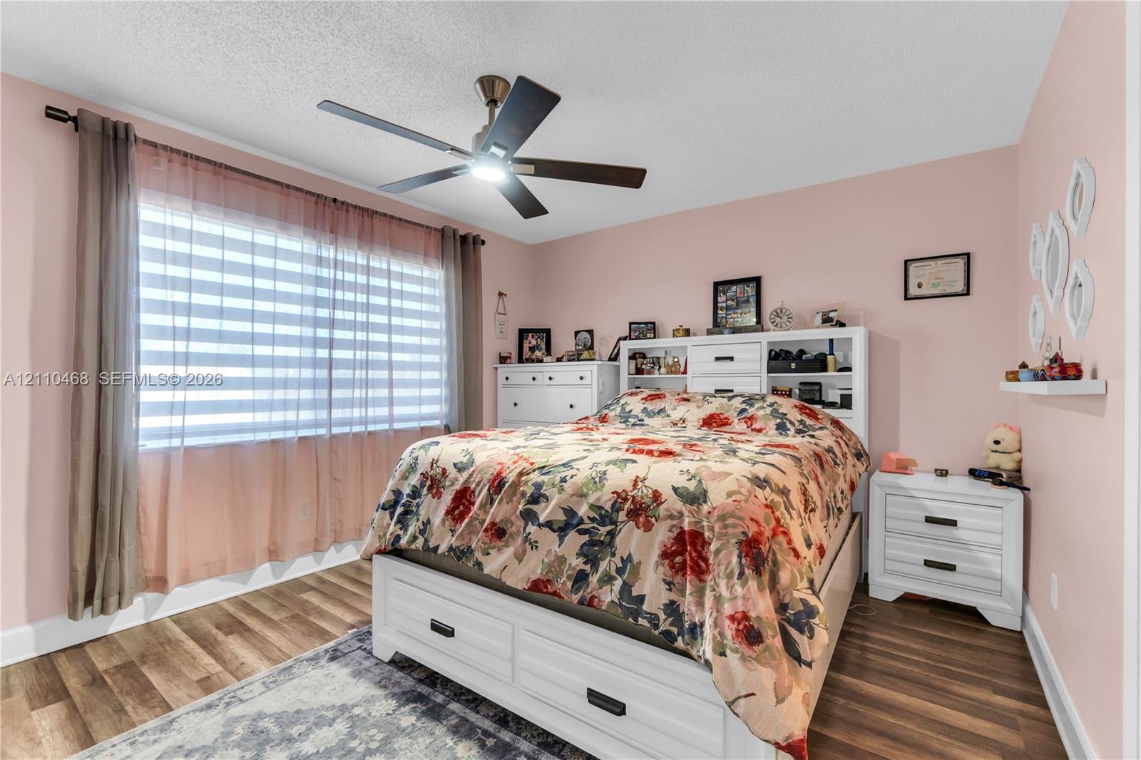 Wood-finish flooring, multi-pane window, and a central ceiling fan with integrated lighting