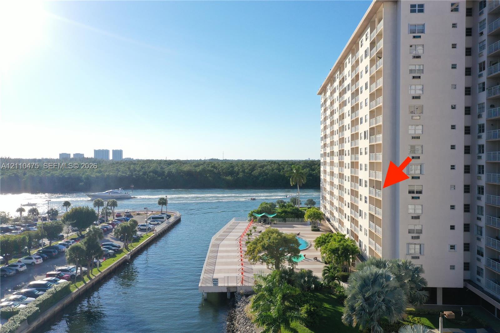 High-rise building featuring private balconies, an outdoor swimming pool, paved waterfront deck, and direct access to the waterway