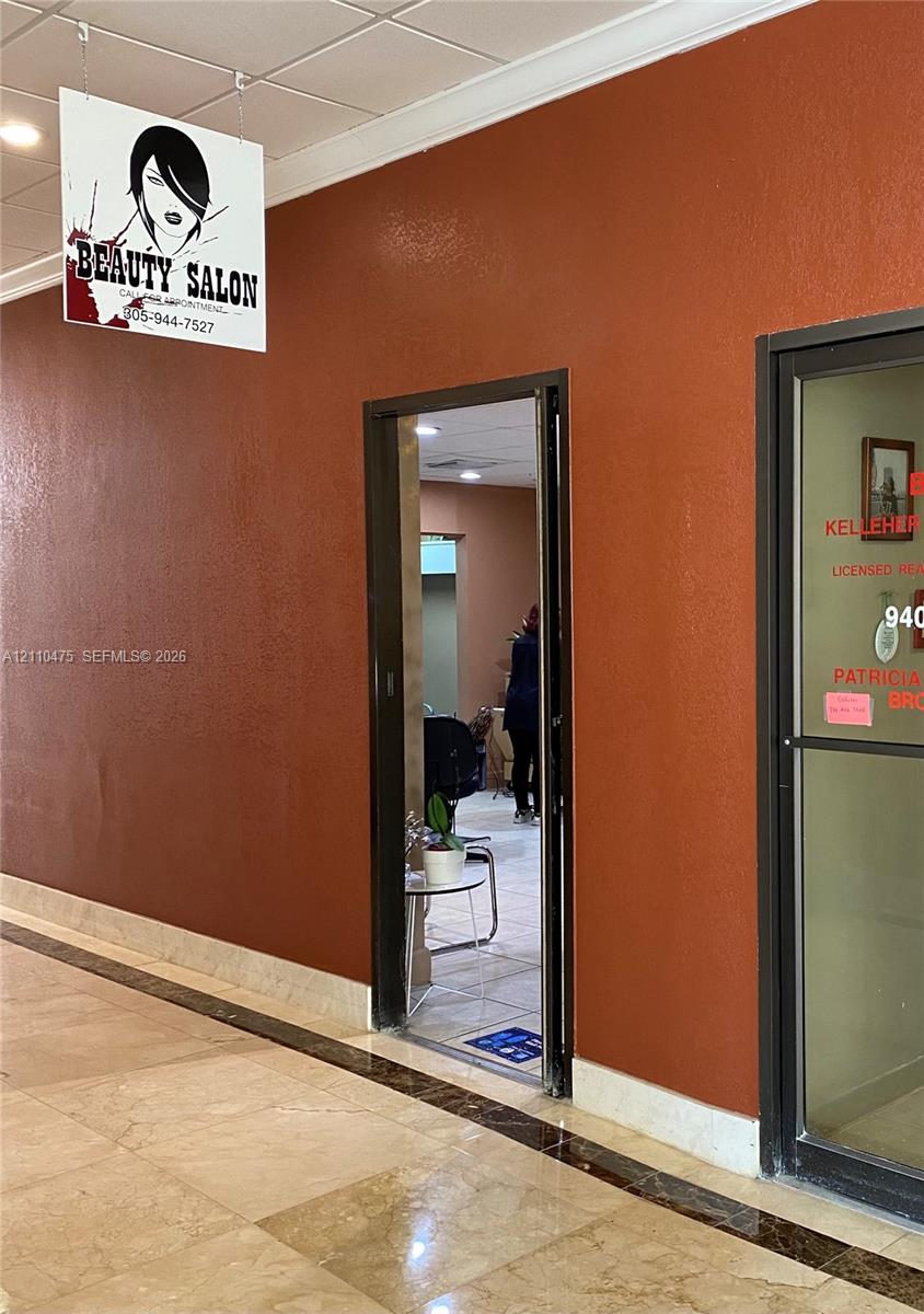 Commercial entry featuring a dark metal door frame, suspended ceiling, and polished stone flooring with decorative inlay