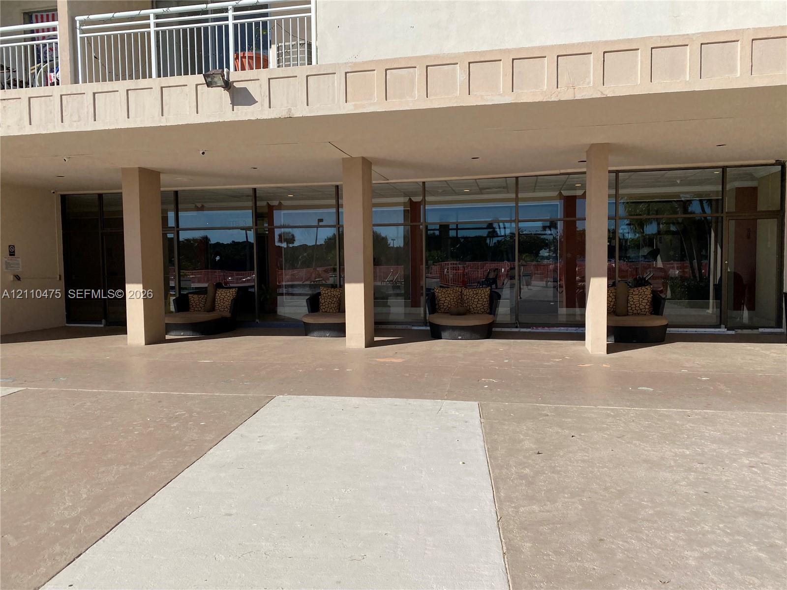 Covered concrete patio featuring floor-to-ceiling glass paneling and structural support columns