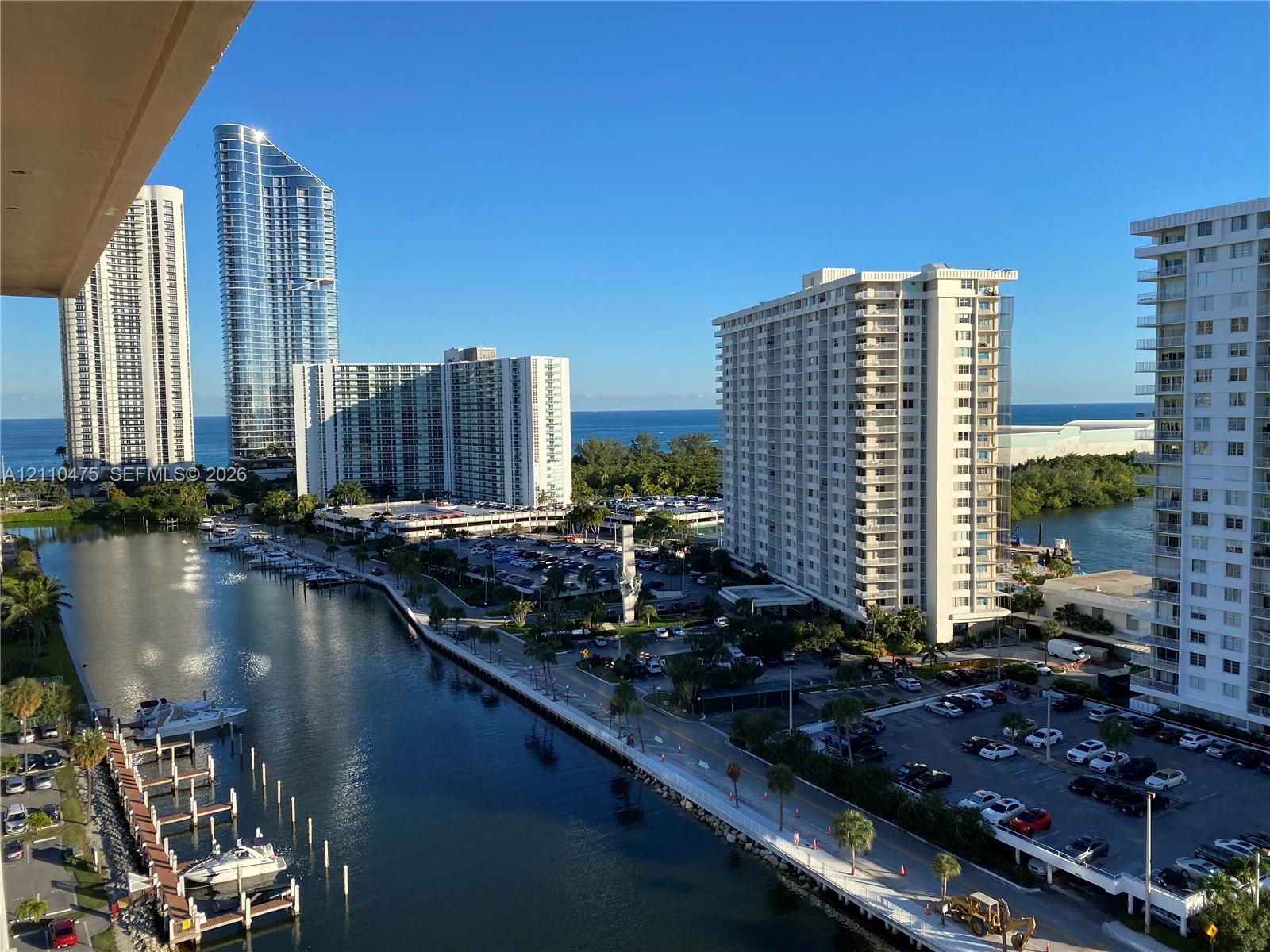 Elevated balcony overlooking a coastal waterway, deep-water boat slips, and an expansive ocean horizon