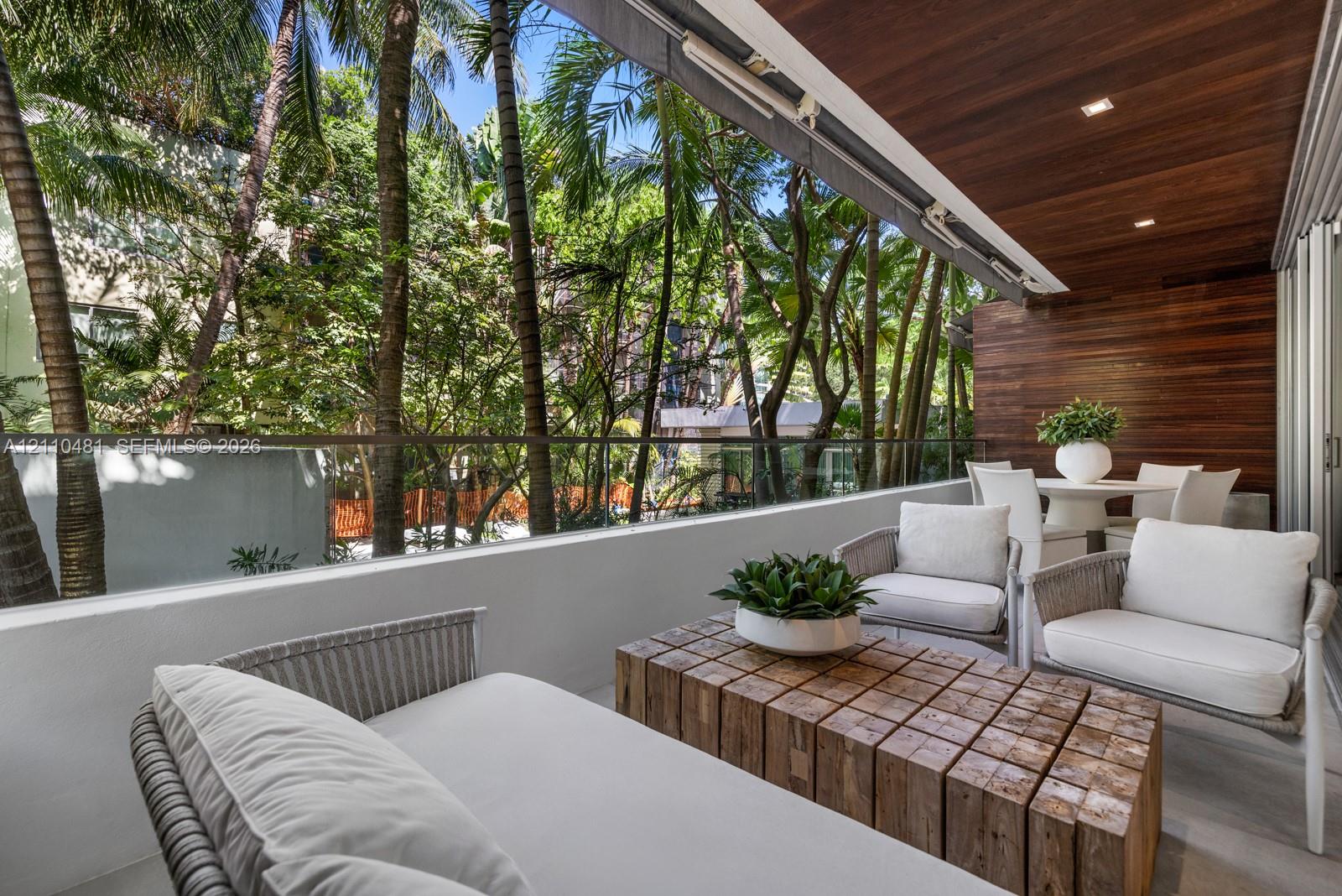 Covered balcony featuring wood-plank ceiling and wall cladding, glass pane railing, and recessed lighting