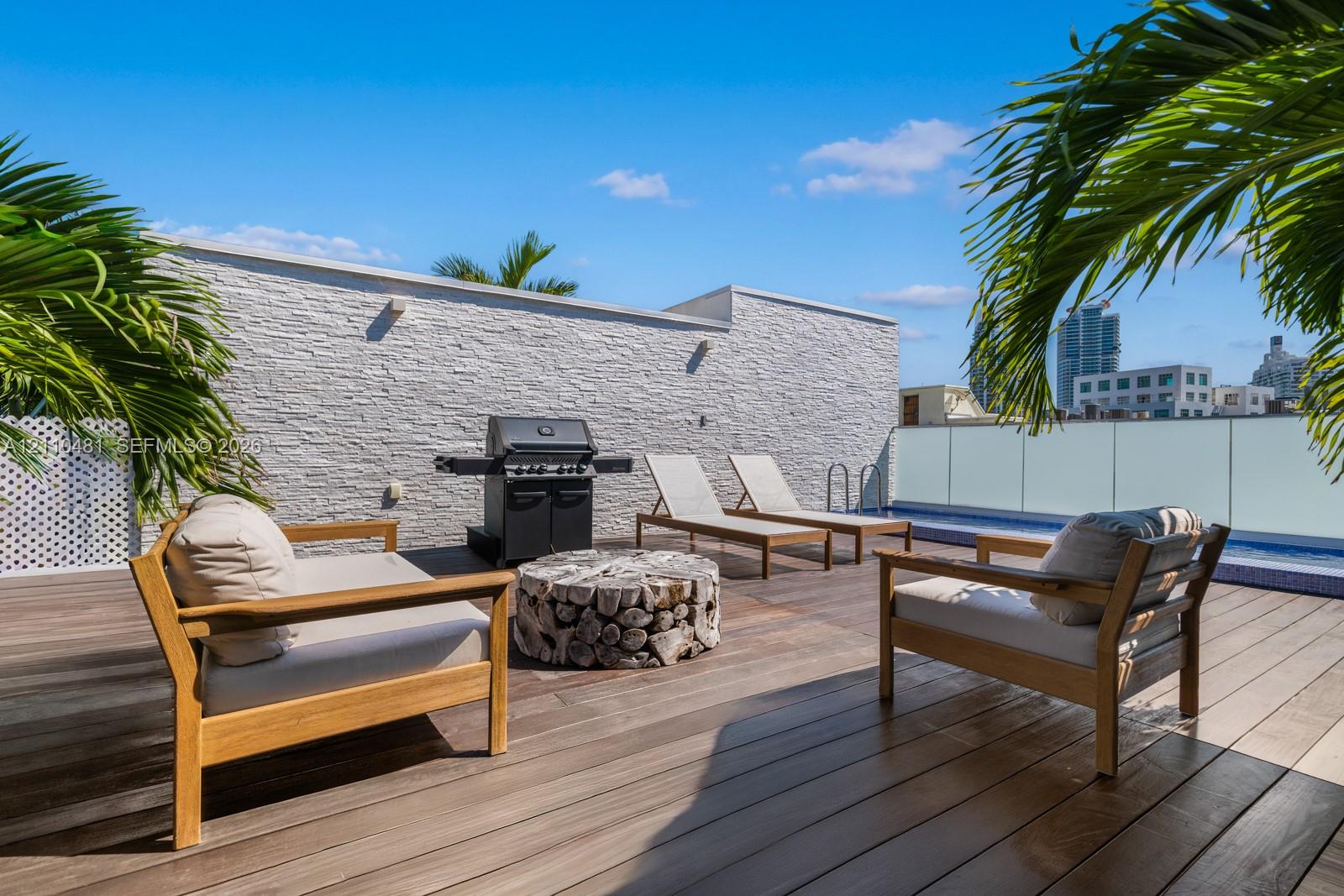 Rooftop terrace featuring wood-finish decking, a textured stone accent wall, and a perimeter glass railing system