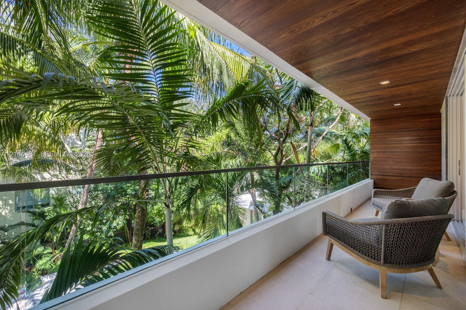 Covered balcony featuring wood-paneled ceiling, glass panel railing, and stone tile flooring