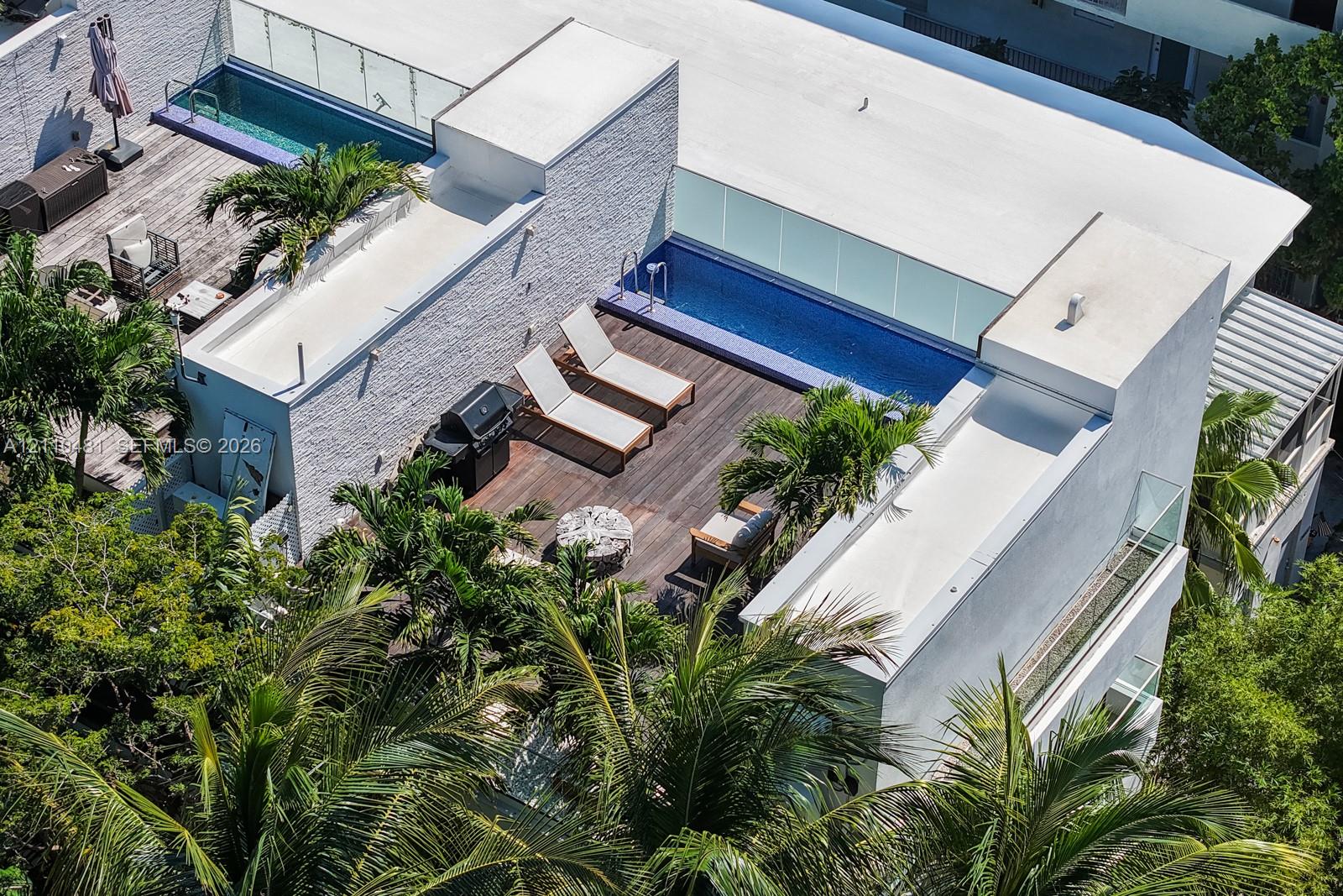Rooftop terrace featuring wood decking, tiled pool, glass railing, and textured exterior wall cladding