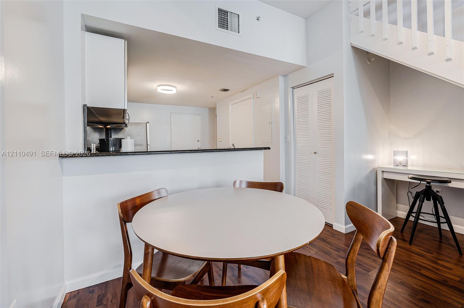 Kitchen featuring a dark stone countertop, wood-finish flooring, and a built-in staircase with white wooden railings