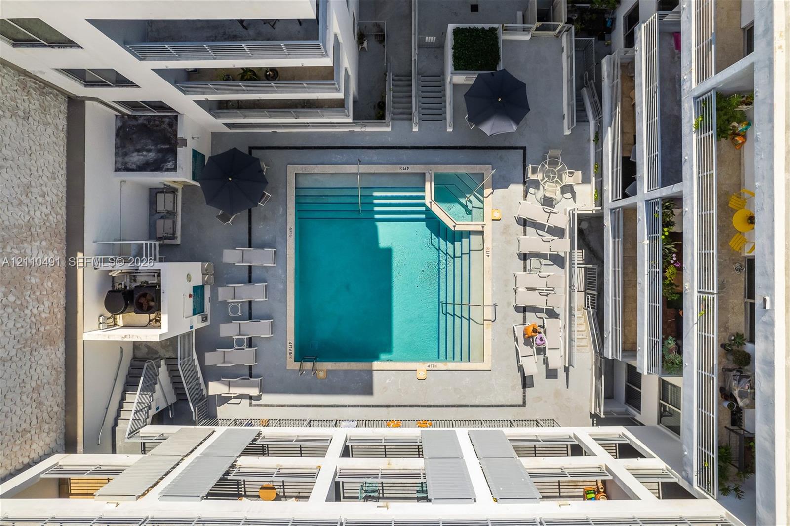 Courtyard featuring an in-ground swimming pool with integrated tiered entry steps and a surrounding concrete deck
