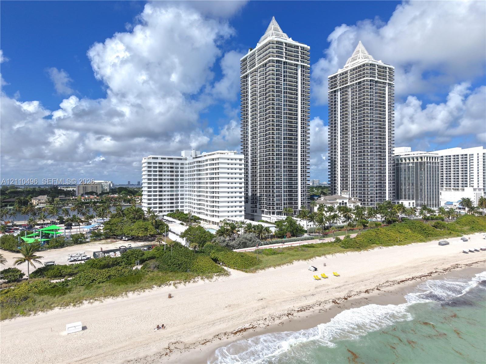 High-rise residential towers featuring expansive floor-to-ceiling balcony glass, peaked architectural rooflines, and immediate proximity to the Atlantic shoreline