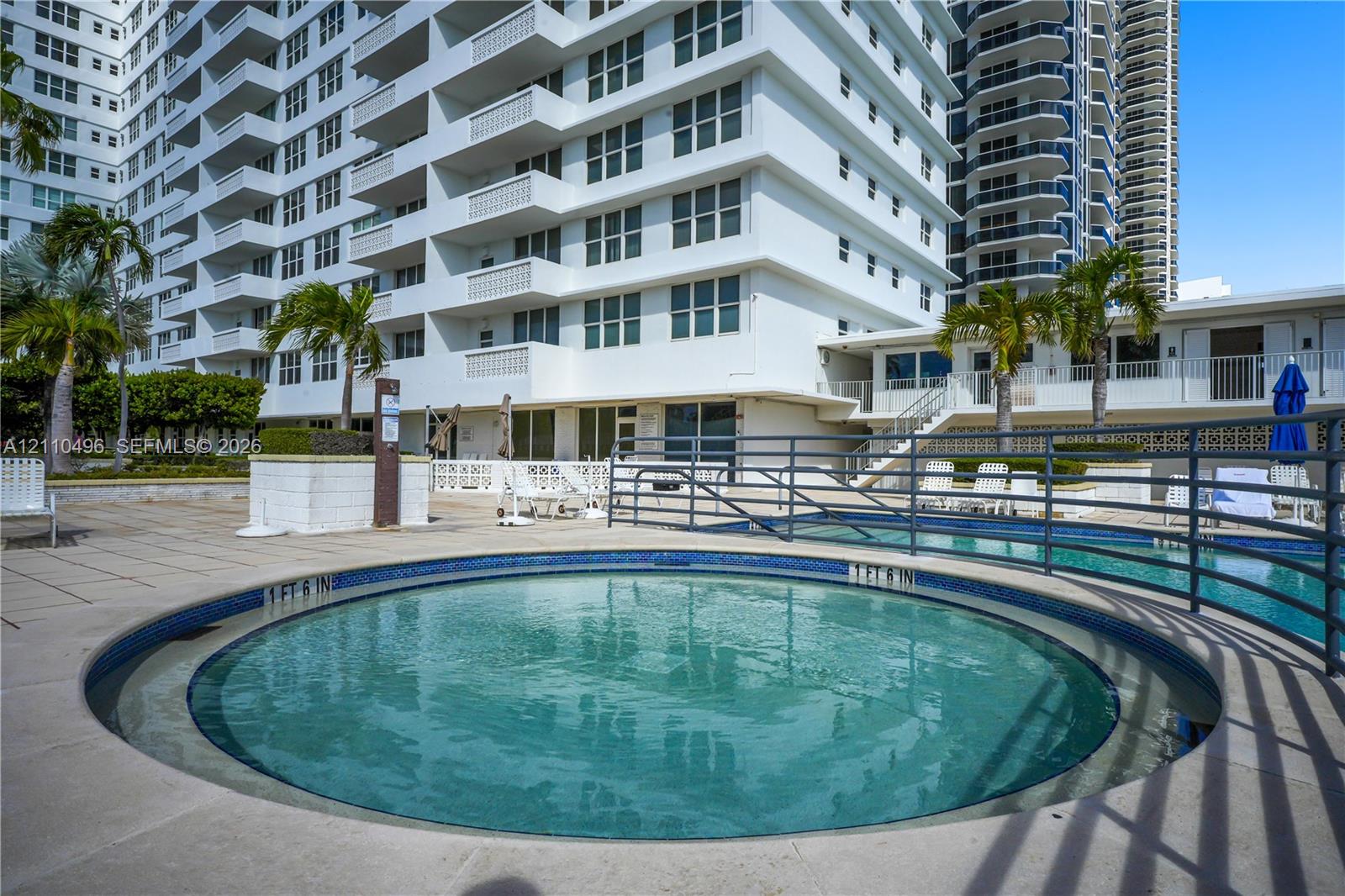 Circular in-ground spa featuring a tiled waterline, concrete deck surround, and metal perimeter railing
