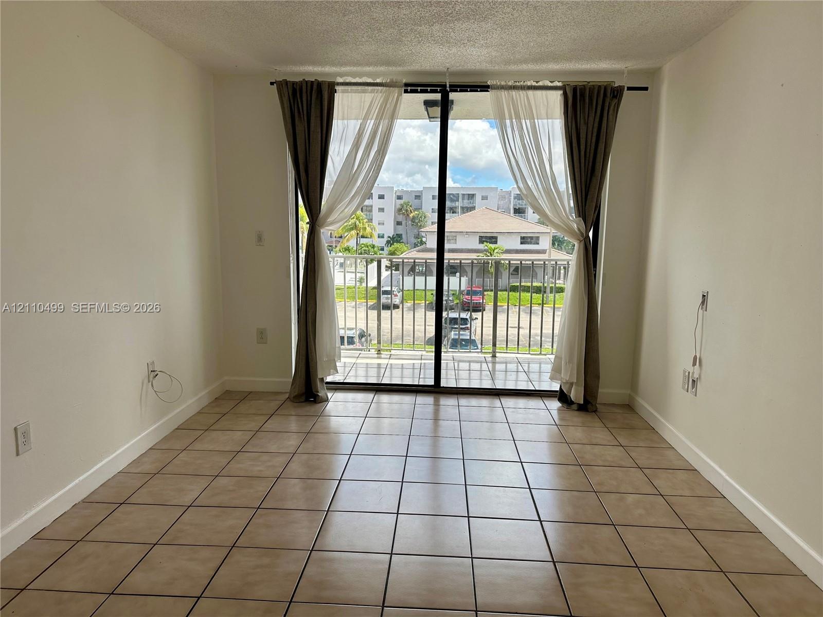 Ceramic tile flooring, sliding glass door, and covered balcony with metal railing