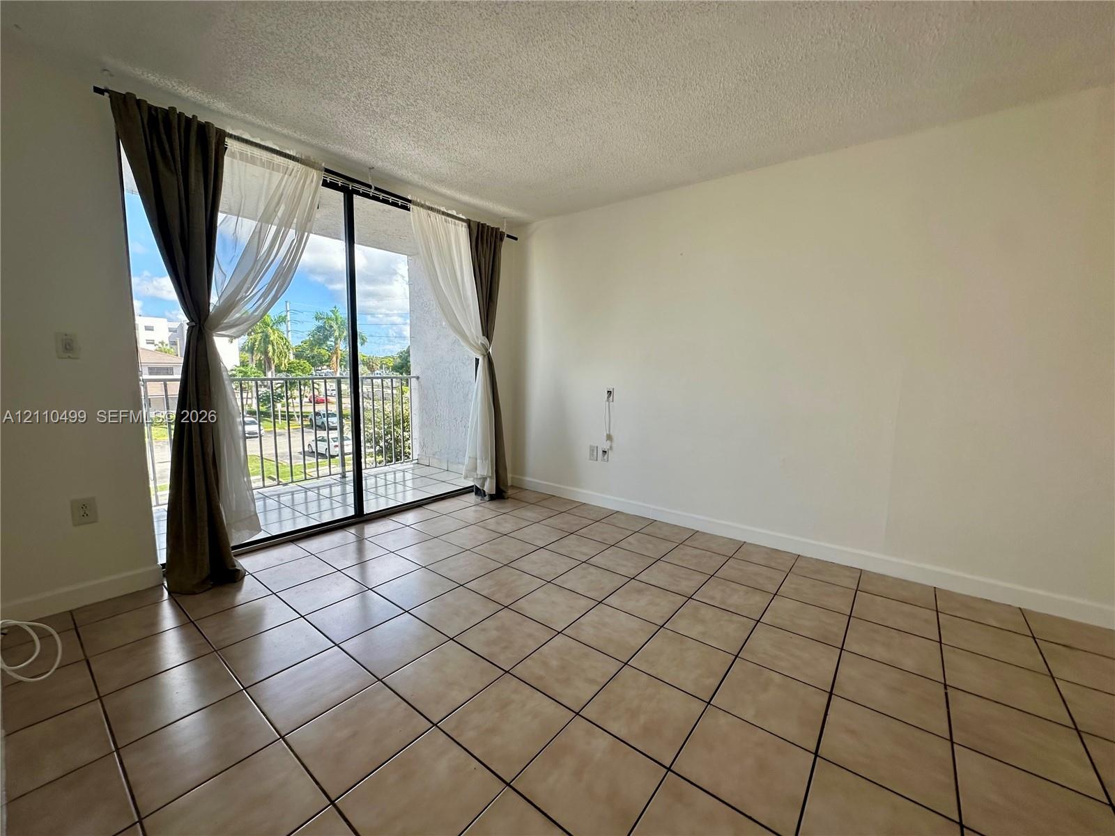 Living area featuring ceramic tile flooring, sliding glass doors, and a private balcony with metal railing