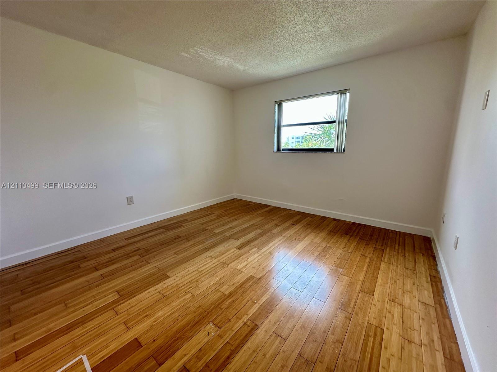 Room featuring wood-finish flooring and a single-pane sliding window