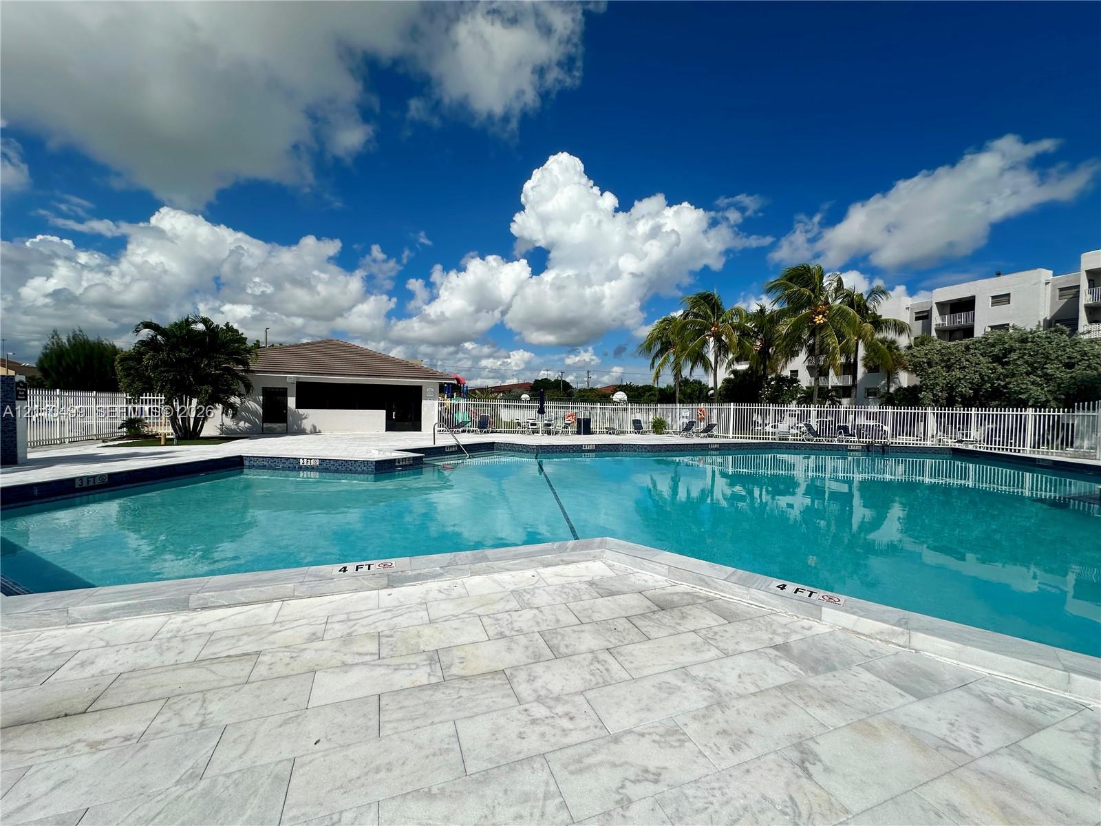Swimming pool featuring tile surround, paved decking, and perimeter fencing