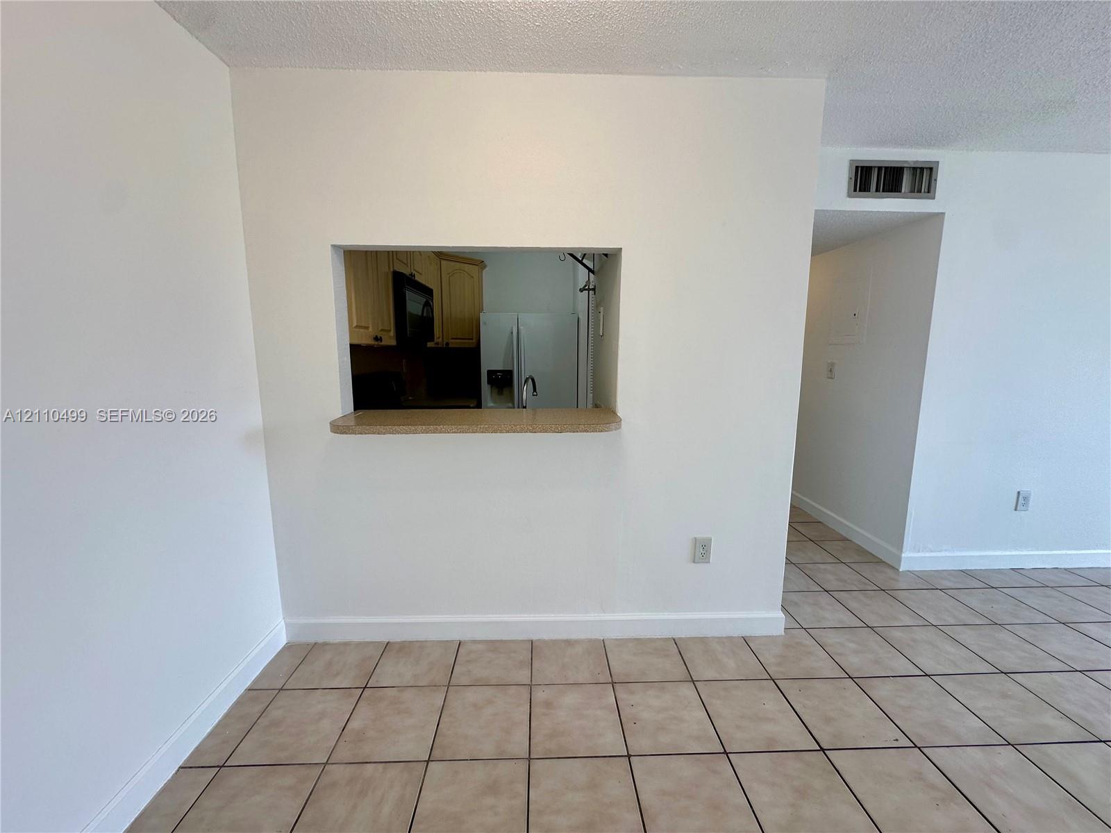 Interior space featuring ceramic tile flooring and a service pass-through opening with a countertop