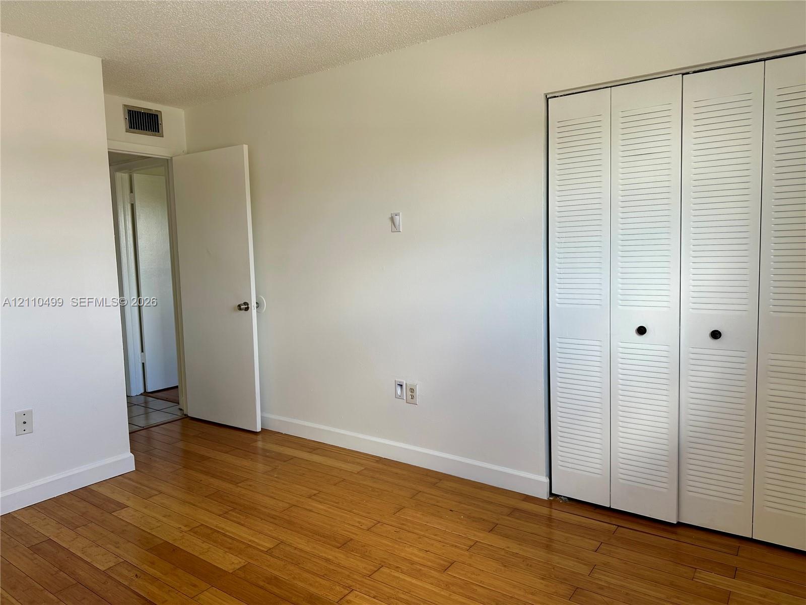 Wood-finish flooring and white louvered bifold closet doors