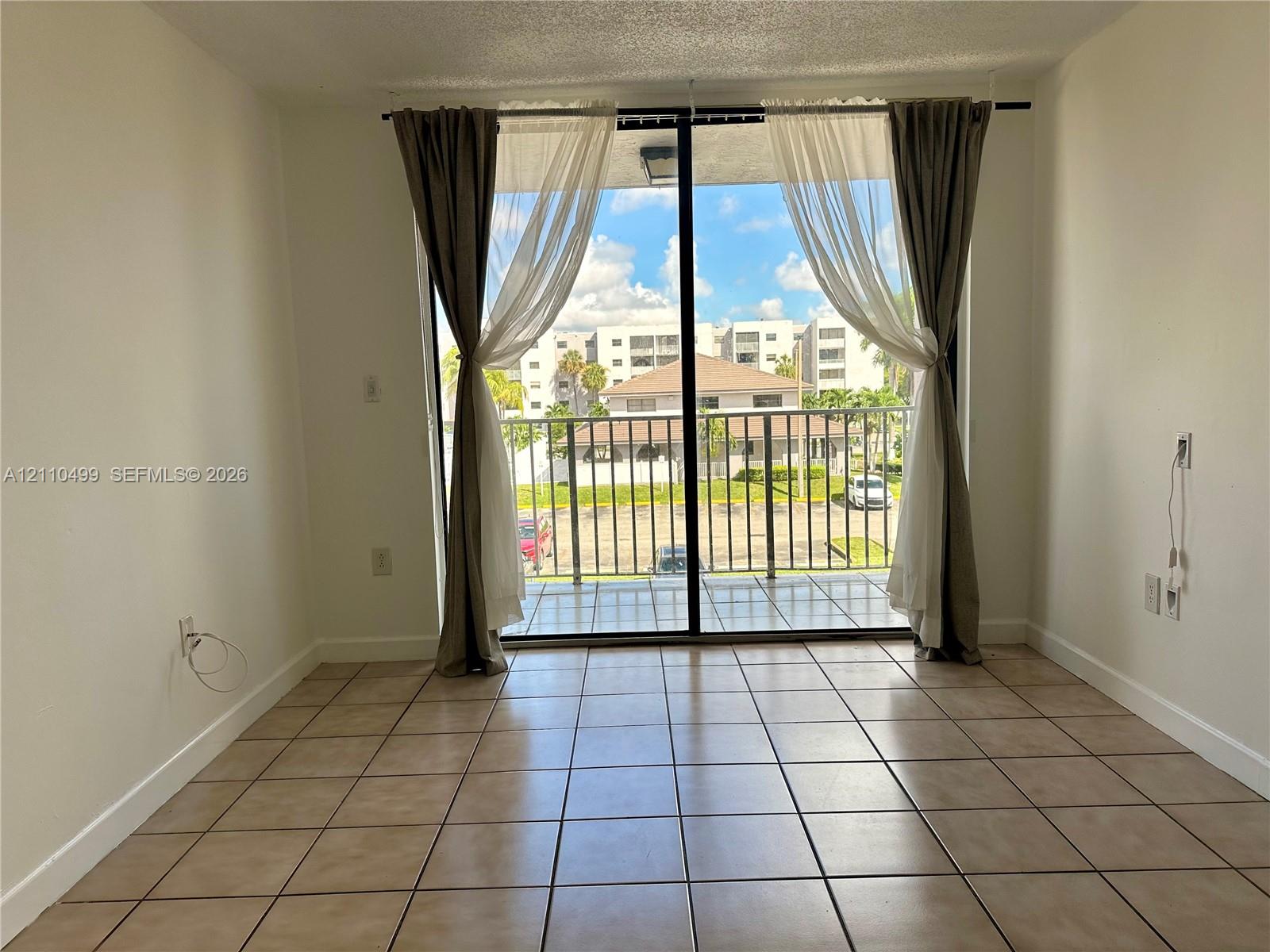 Floor-to-ceiling sliding glass doors opening to a private balcony with metal railing and tile flooring