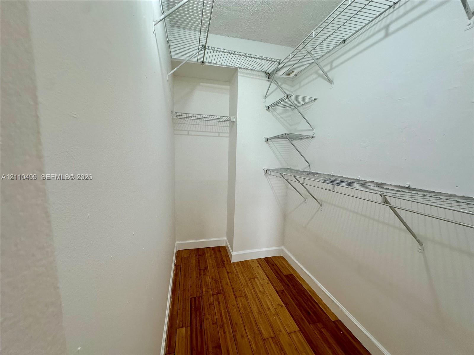 Walk-in closet featuring wood-finish flooring and tiered metal wire shelving