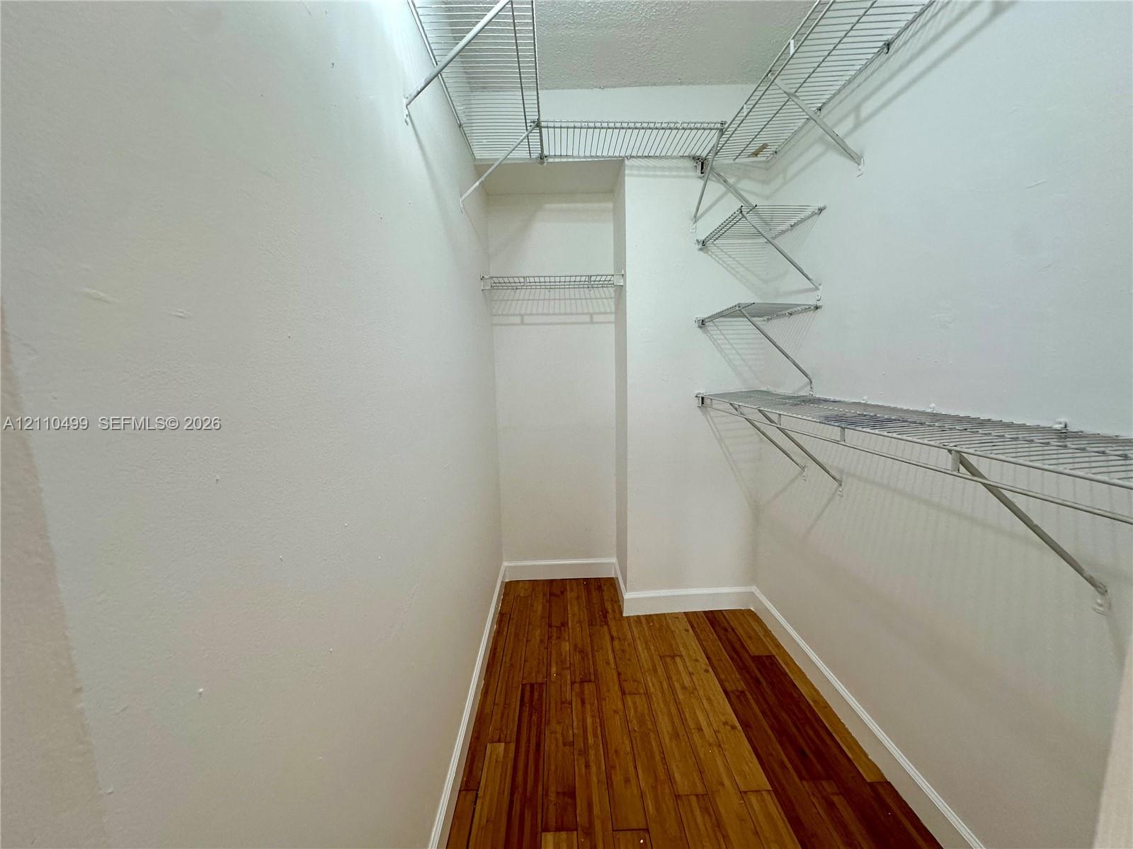 Storage space featuring wood-finish flooring and tiered wire shelving