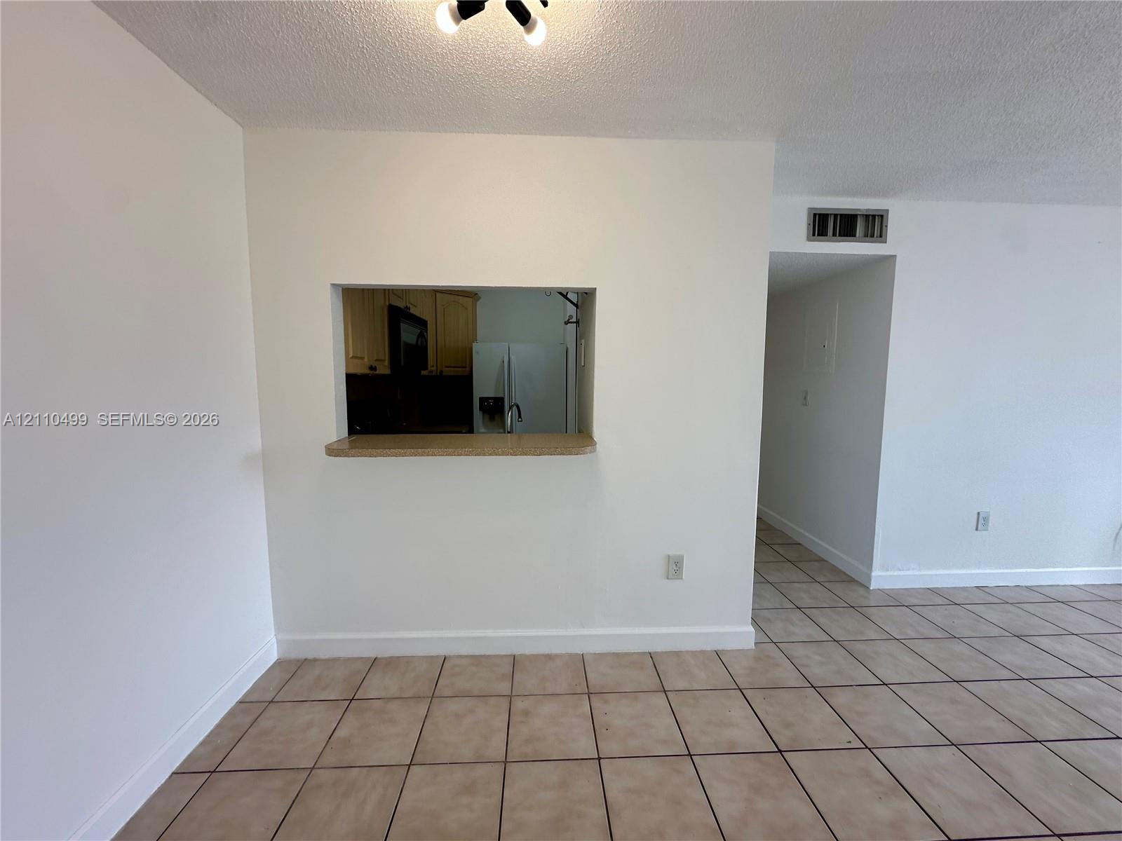 Ceramic tile flooring, interior pass-through window with a countertop ledge, and textured ceiling finish Ceramic tile flooring, interior pass-through window with a countertop ledge, and textured ceiling finish