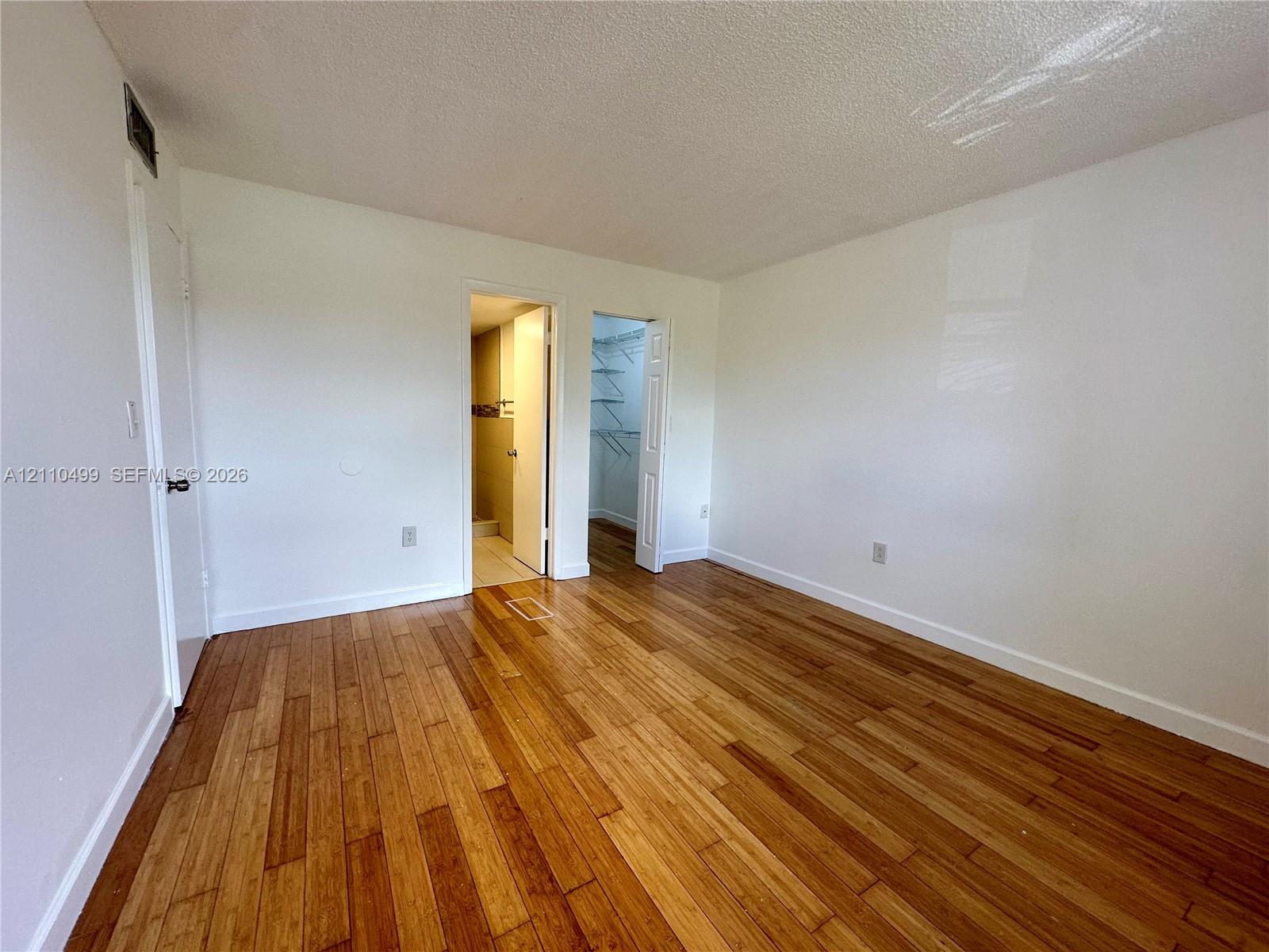 Wood-finish flooring throughout, smooth-texture ceiling, and a built-in closet with wire shelving