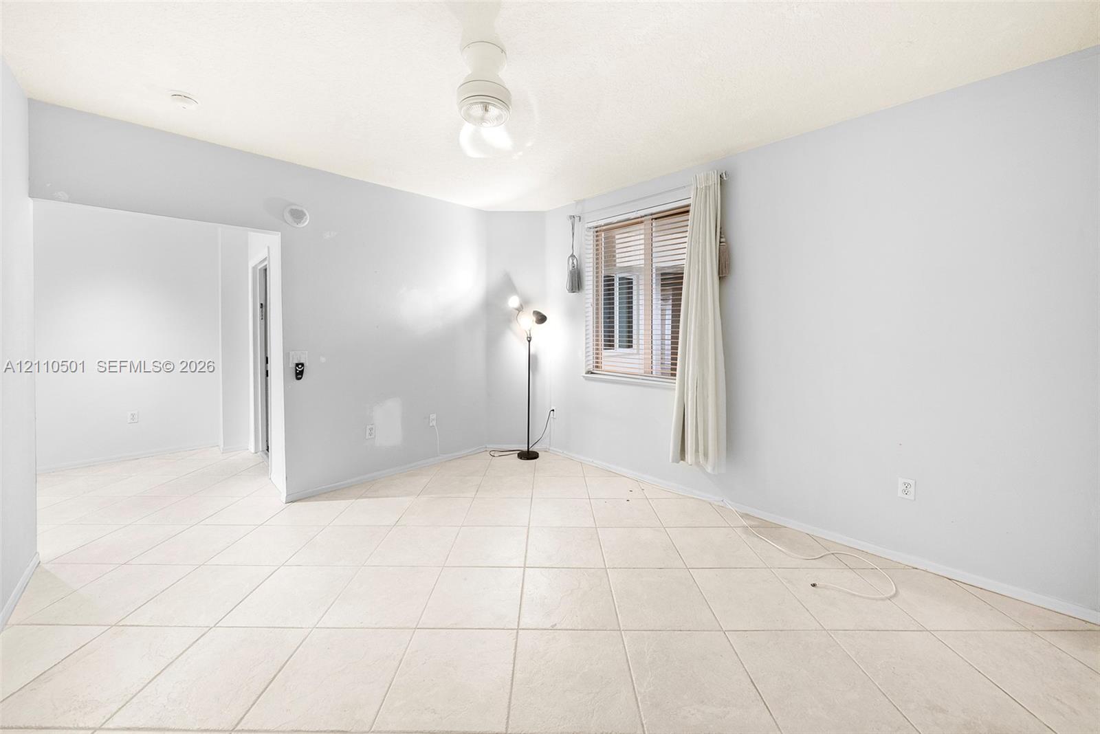 Neutral-toned ceramic tile flooring, ceiling-mounted light fixture, and horizontal blind window covering