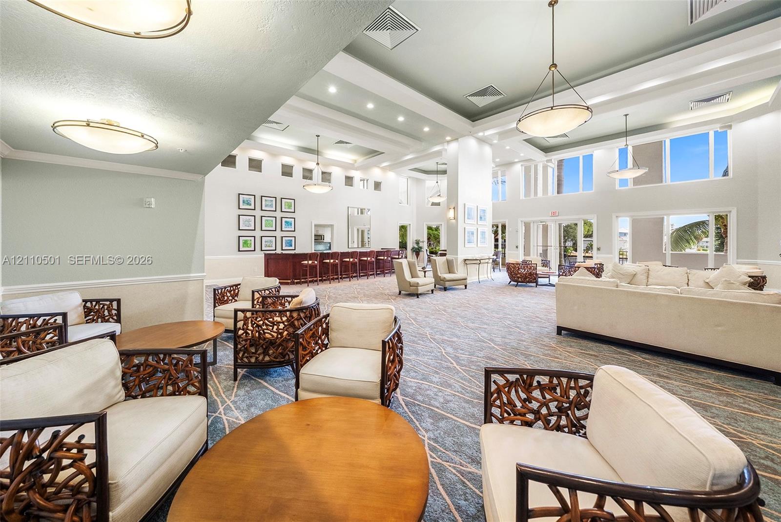 Expansive room featuring recessed lighting, tray ceilings, oversized windows, and a built-in bar area with custom cabinetry