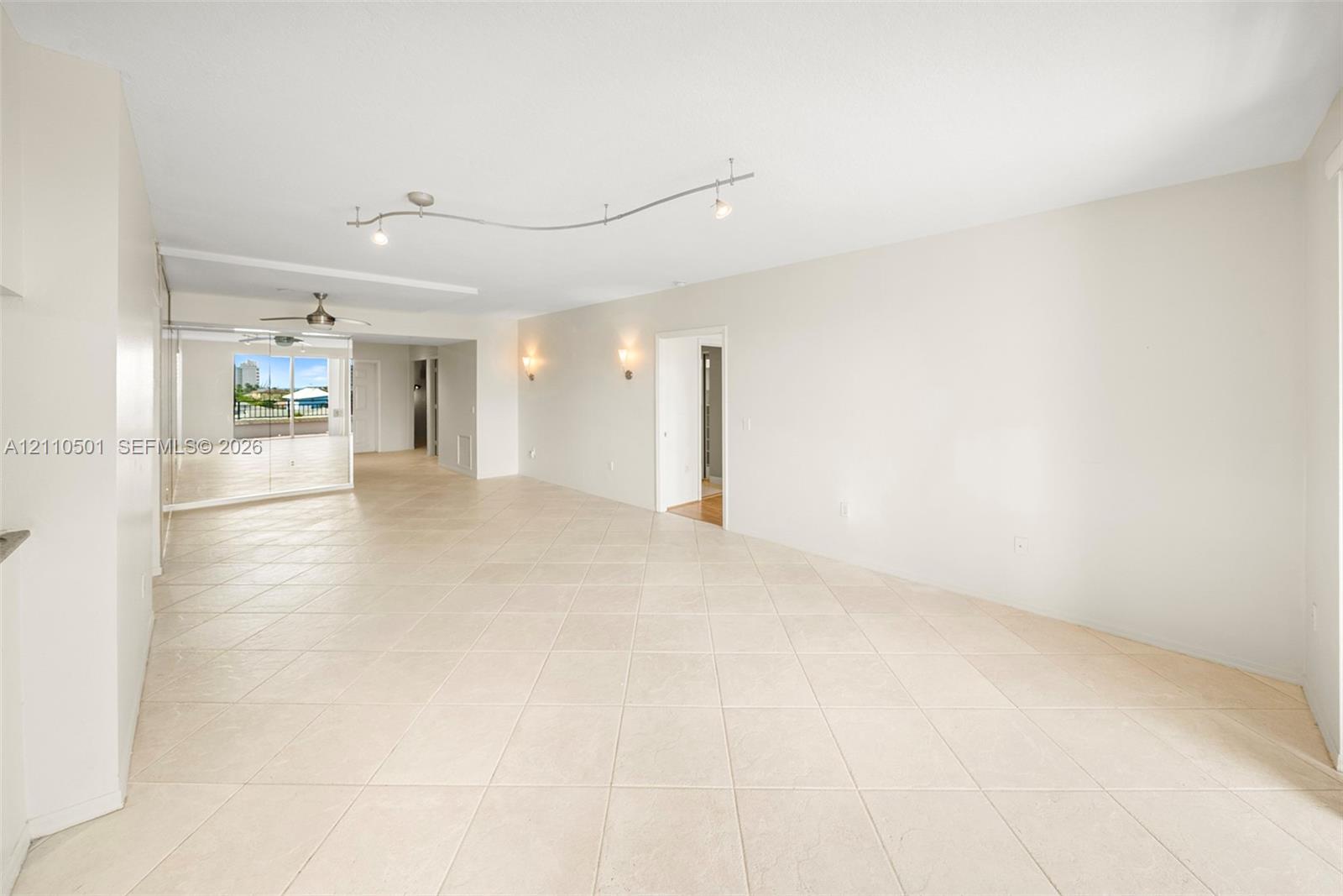 Neutral-toned tile flooring, recessed track lighting, wall-mounted sconces, and full-length mirrored paneling