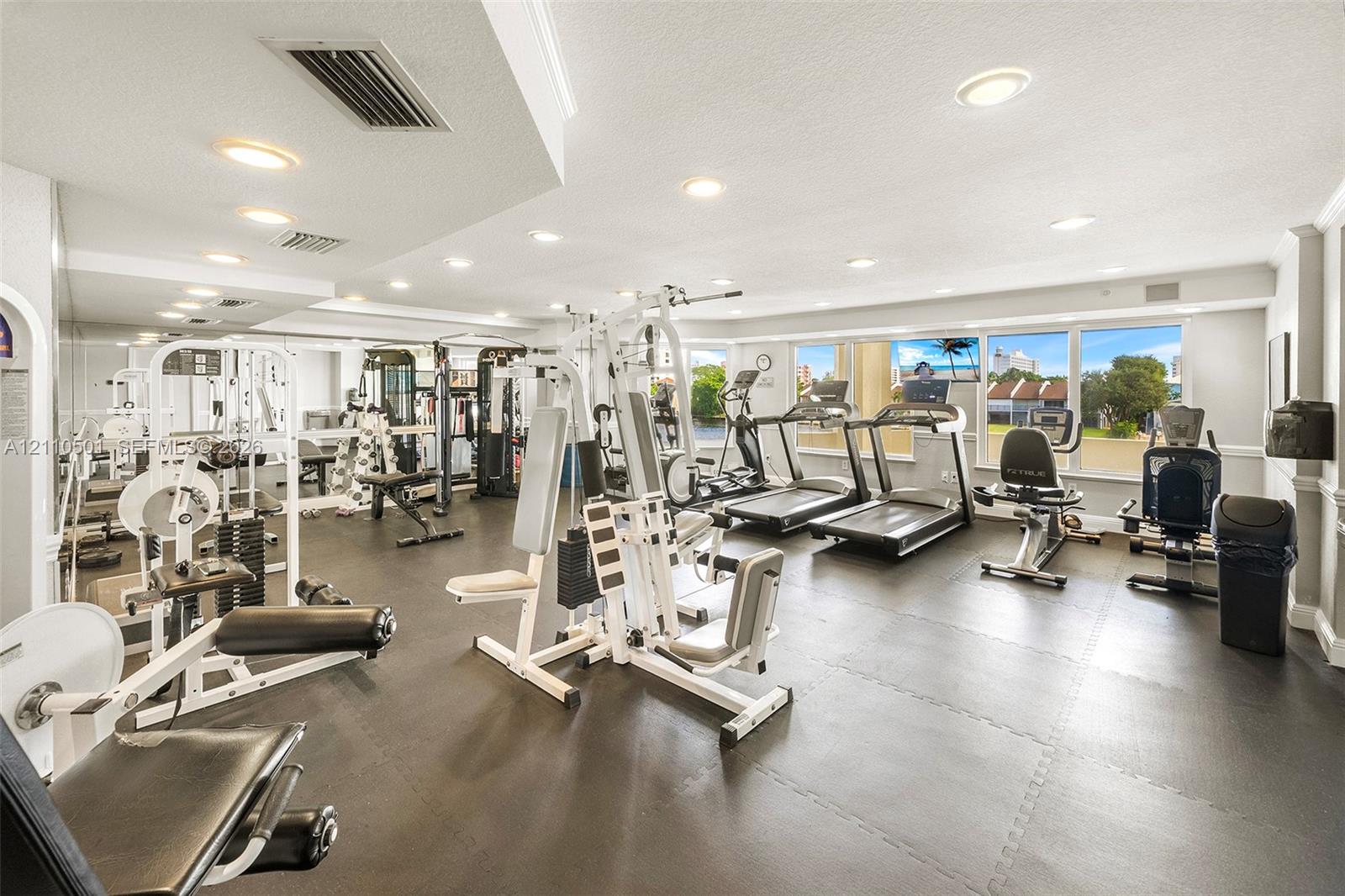 Fitness room featuring a mirrored wall, recessed lighting, rubberized flooring, and large windows