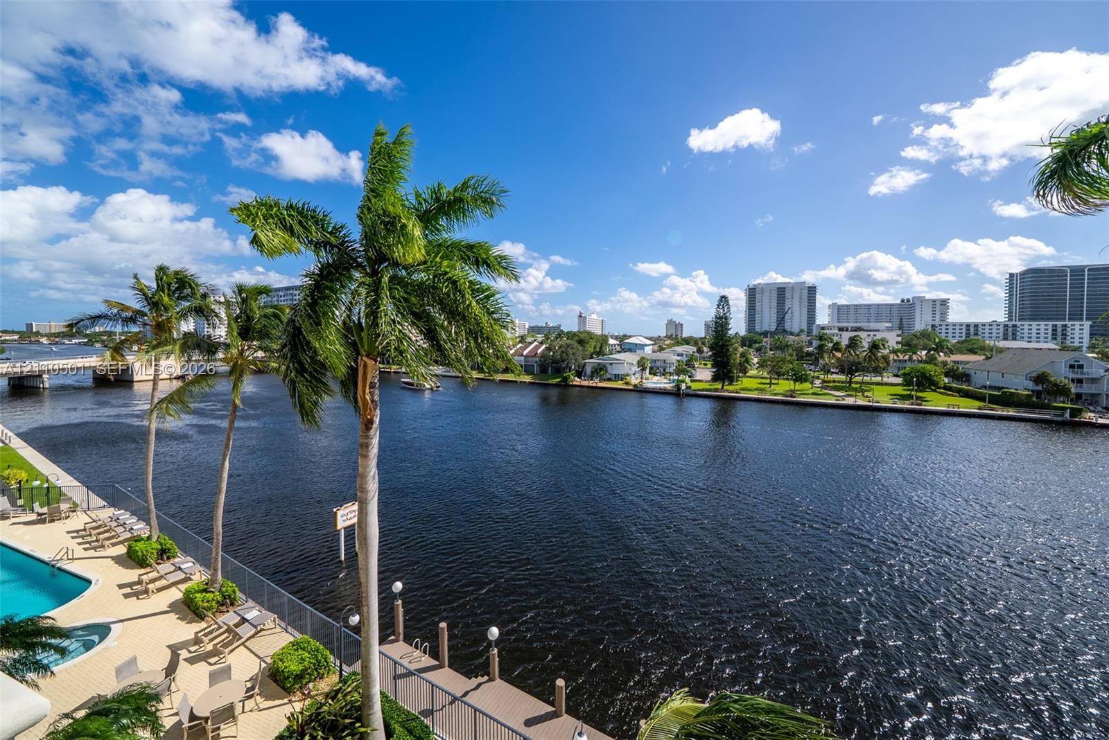 Waterfront property featuring a swimming pool, paved deck, private boat dock, and mature palm trees