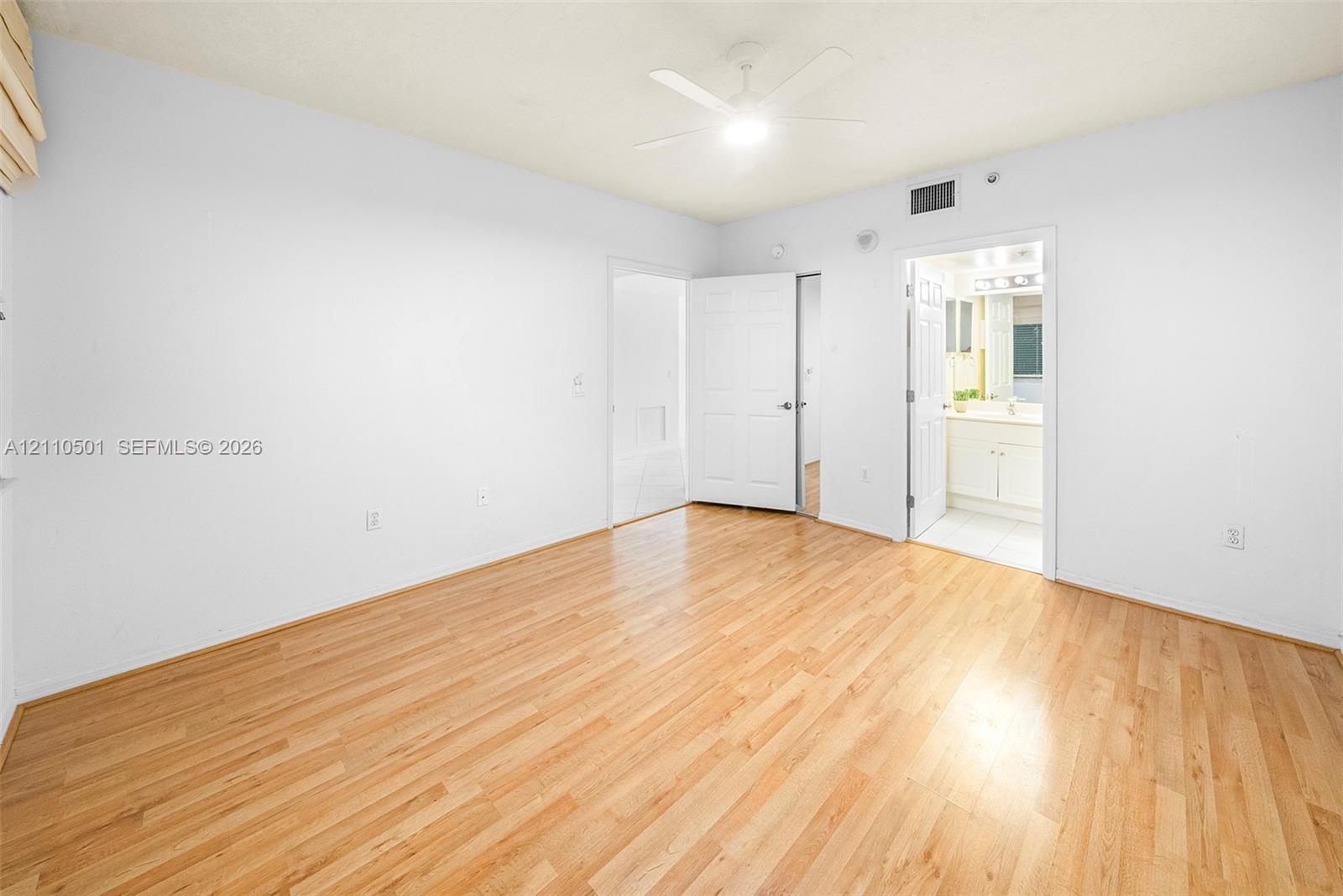 Room featuring wood-finish flooring, a ceiling-mounted light fixture with fan, and white paneled doors