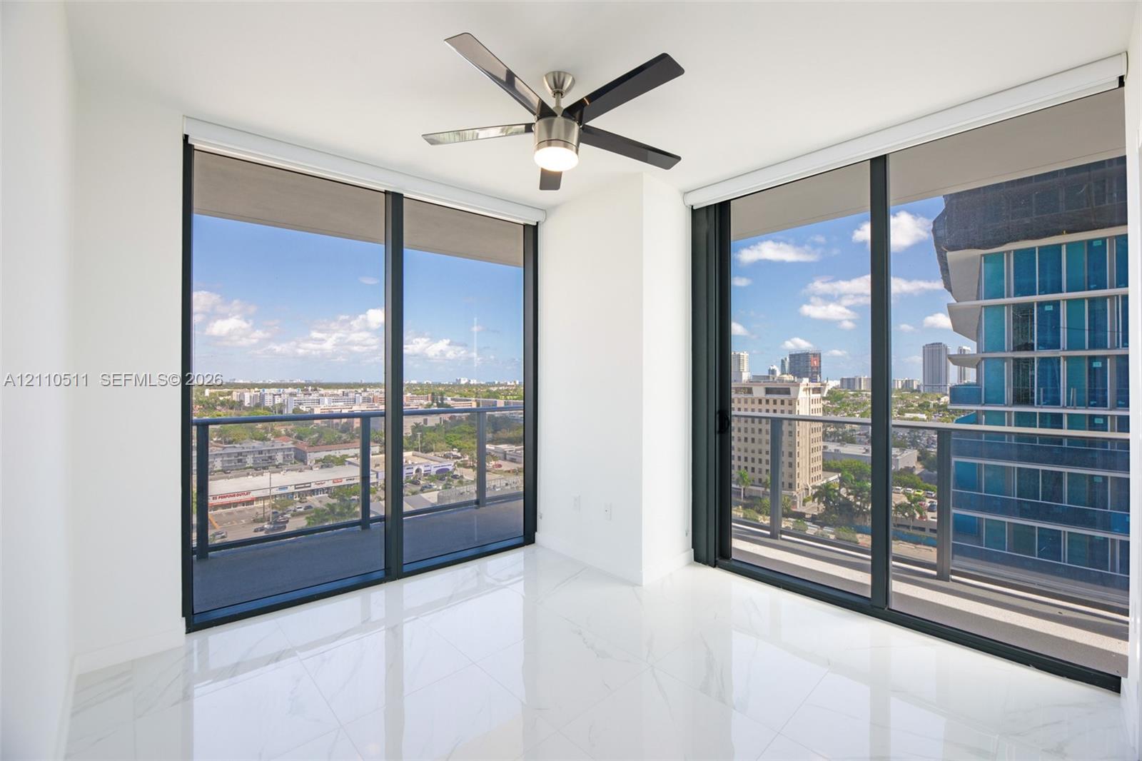 Third bedroom, floor-to-ceiling windows, polished stone-finish flooring, integrated balcony access, and a multi-blade ceiling fan with light fixture