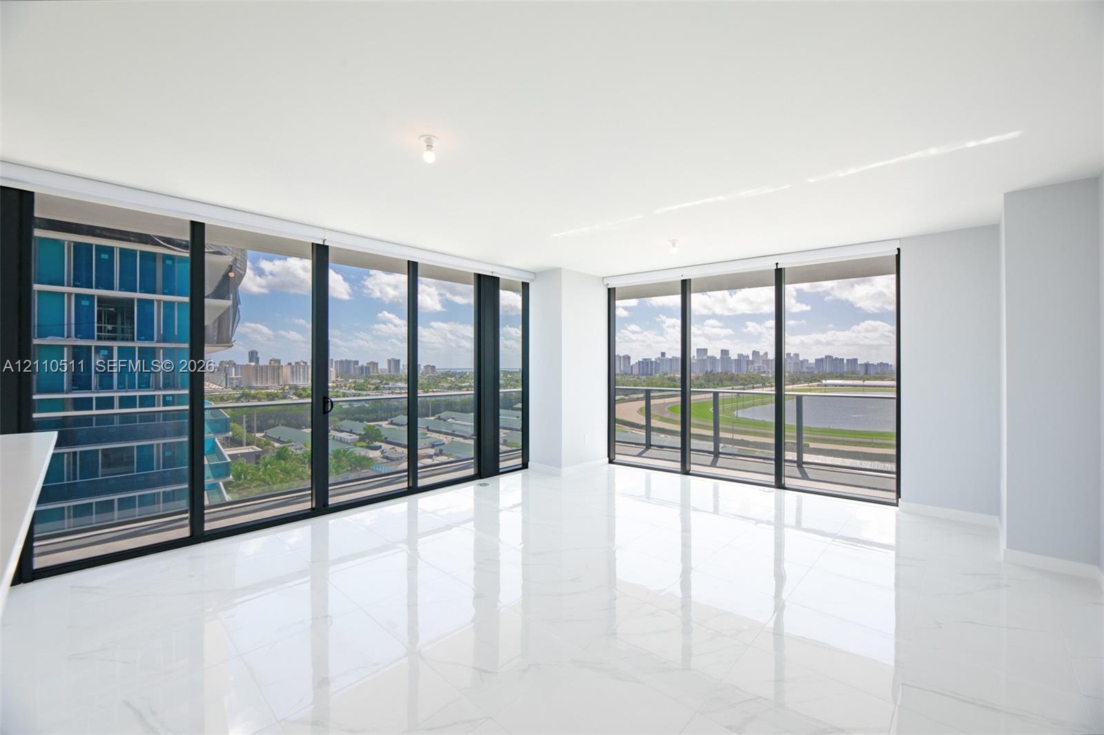 Floor-to-ceiling glass walls, polished white tile flooring, expansive corner layout, and structural balcony railing