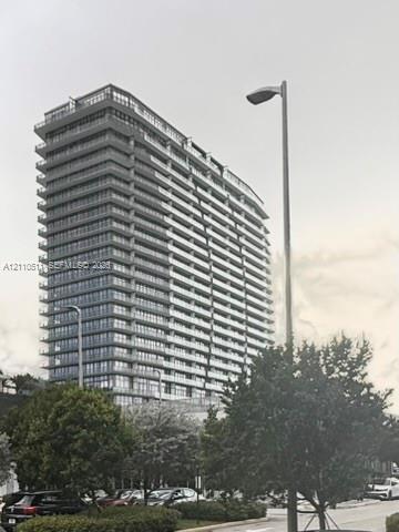 High-rise residential building featuring a glass facade, multiple levels of balconies with glass railings, and a tiered architectural design
