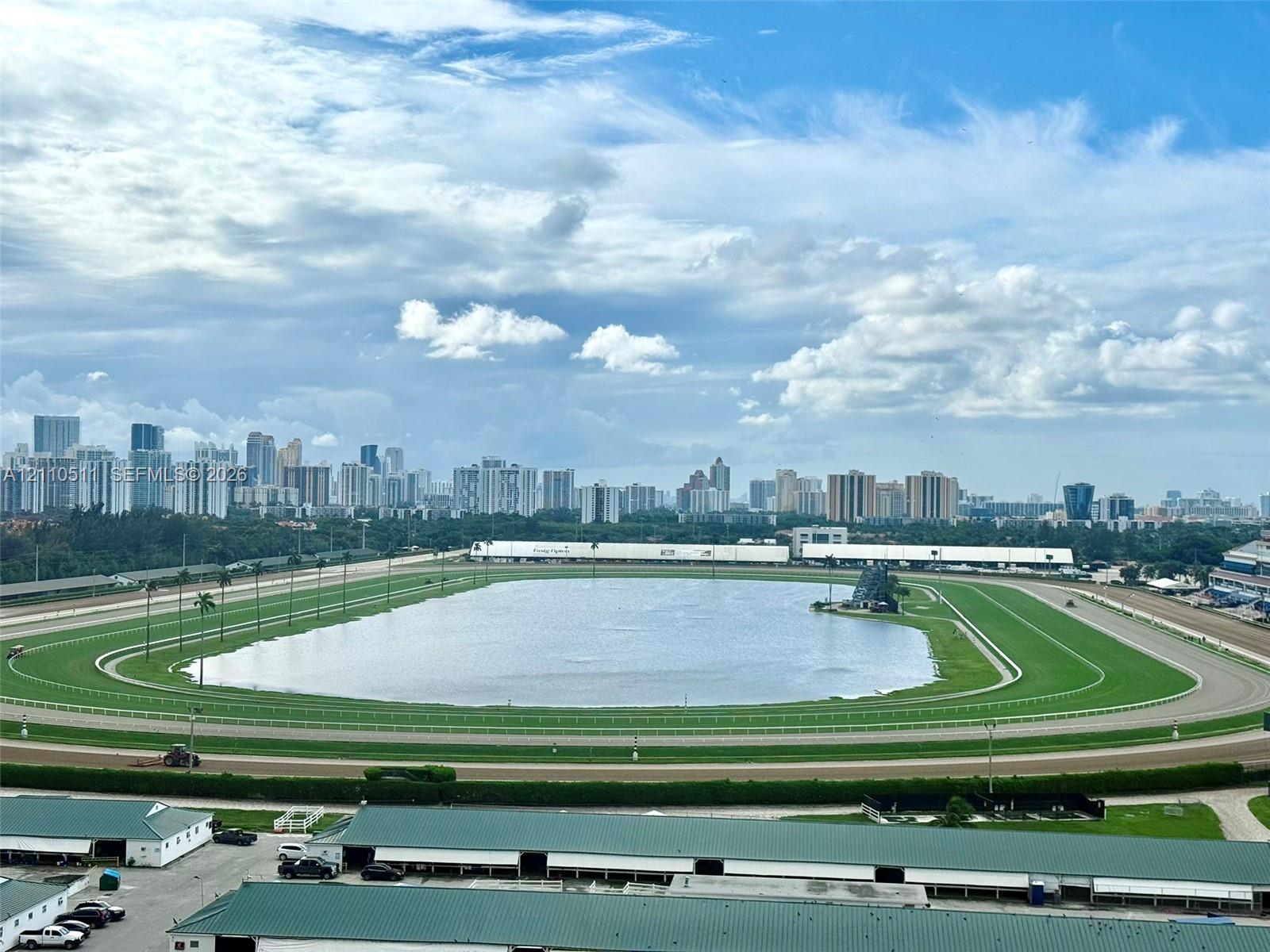 Panoramic perspective featuring a race track, central lake, and city skyline backdrop