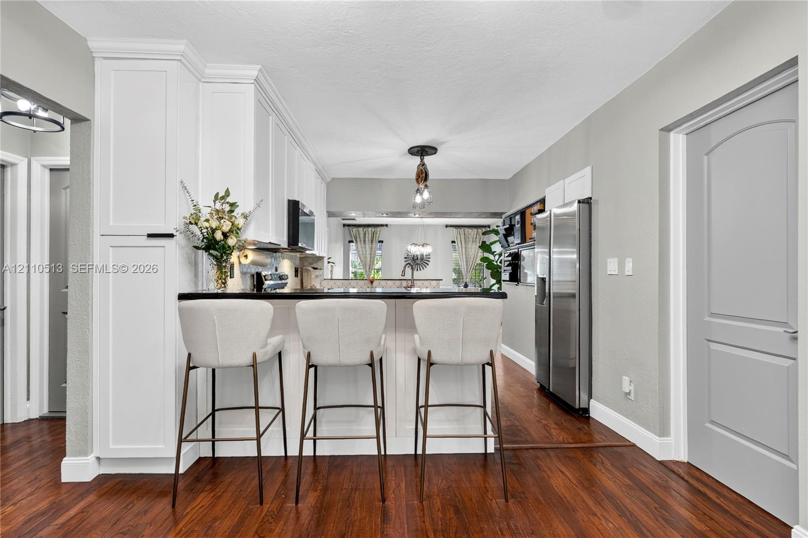 Kitchen featuring white cabinetry, dark countertops, wood-finish flooring, stainless steel refrigerator, and recessed ceiling lighting