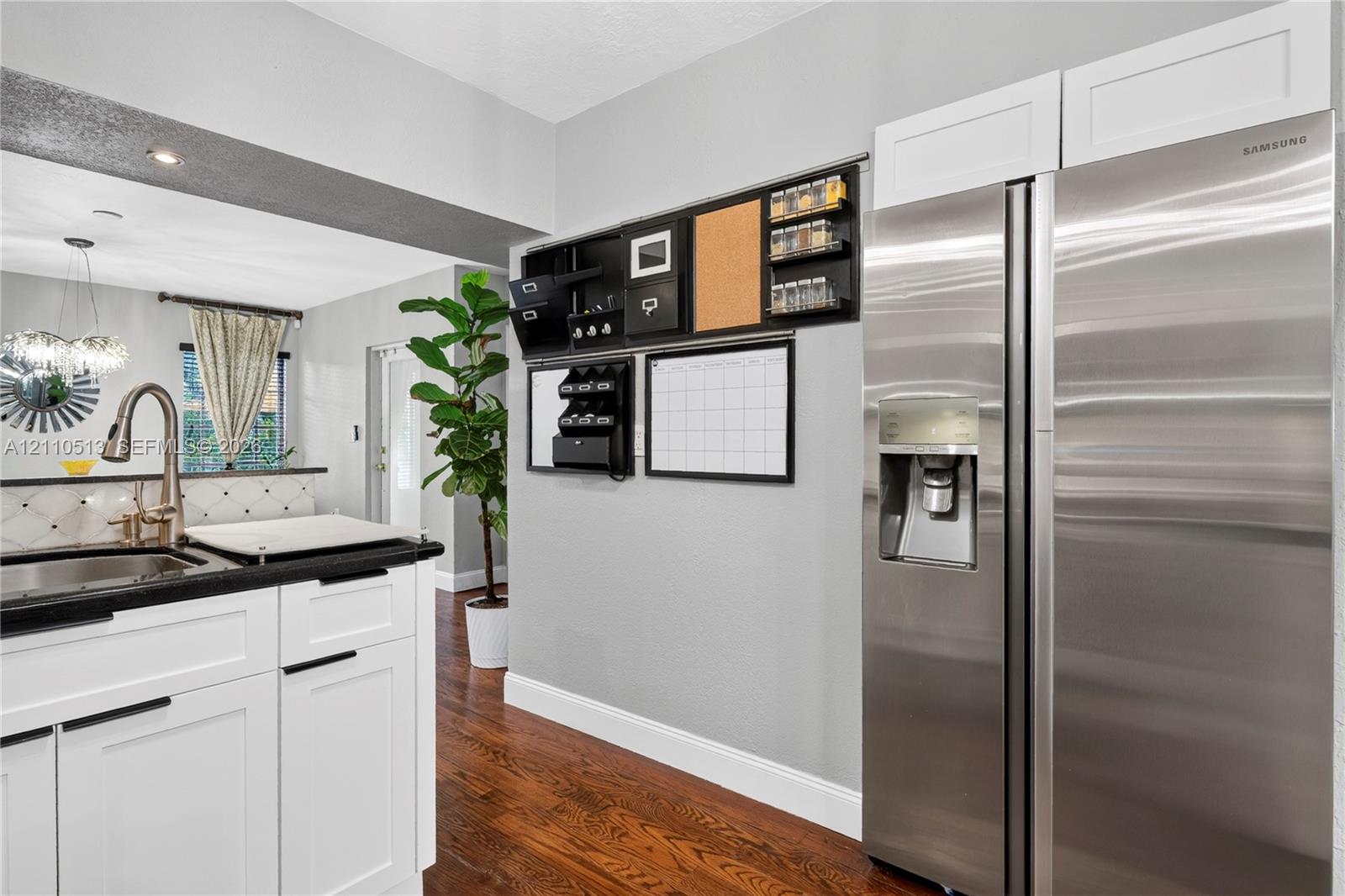 Kitchen featuring white shaker-style cabinetry, stainless steel refrigerator, dark stone-finish countertops, and wood-finish flooring