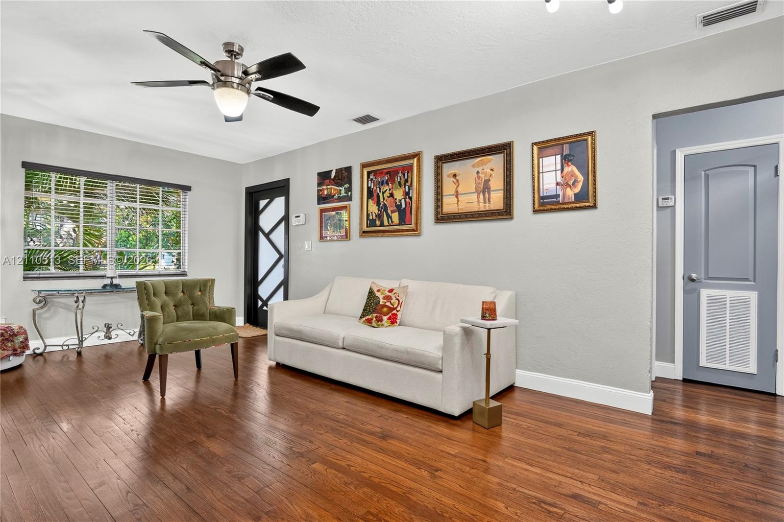 Living area featuring wood-finish flooring, a multi-pane glass entry door, and a central ceiling fan