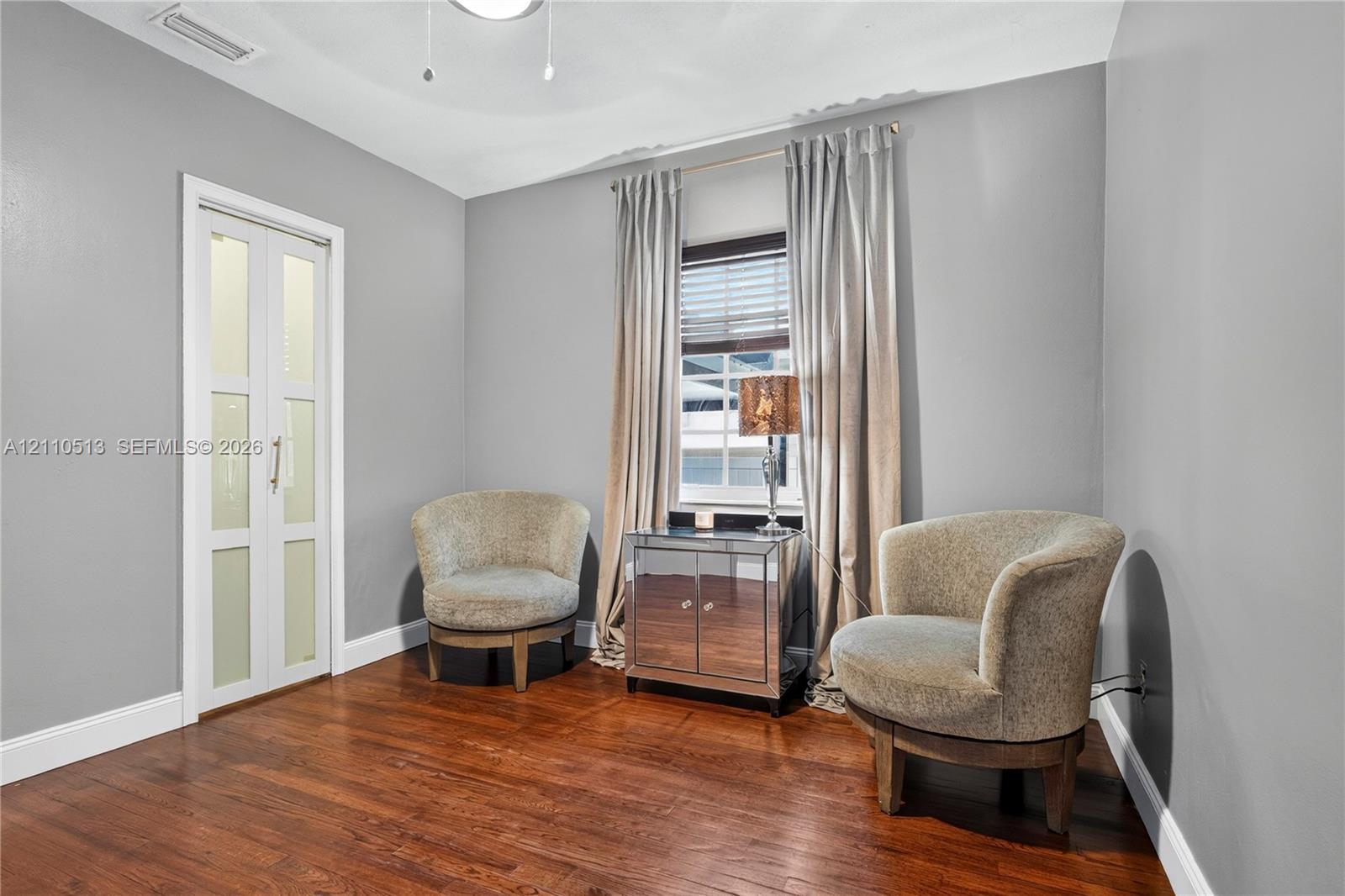 Interior space featuring wood-finish flooring, neutral wall paint, and a bi-fold door with frosted glass panes