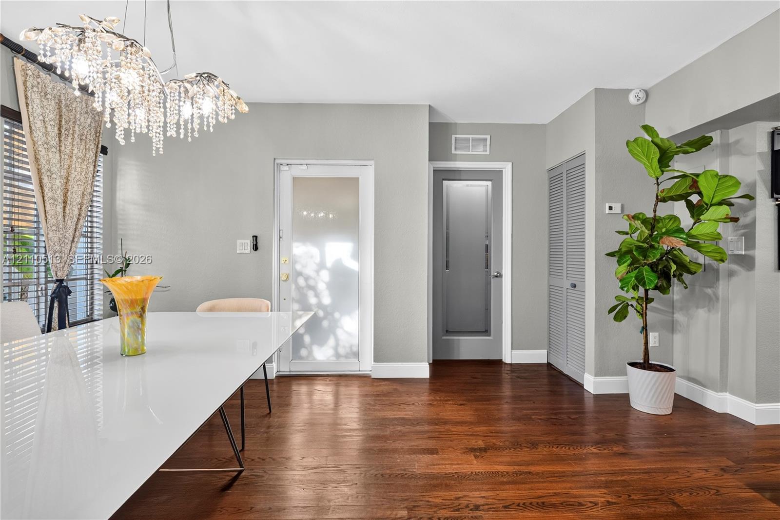 Interior space featuring wood-finish flooring, a multi-tiered crystal chandelier, a glass-panel exterior door, and louvered-style closet doors