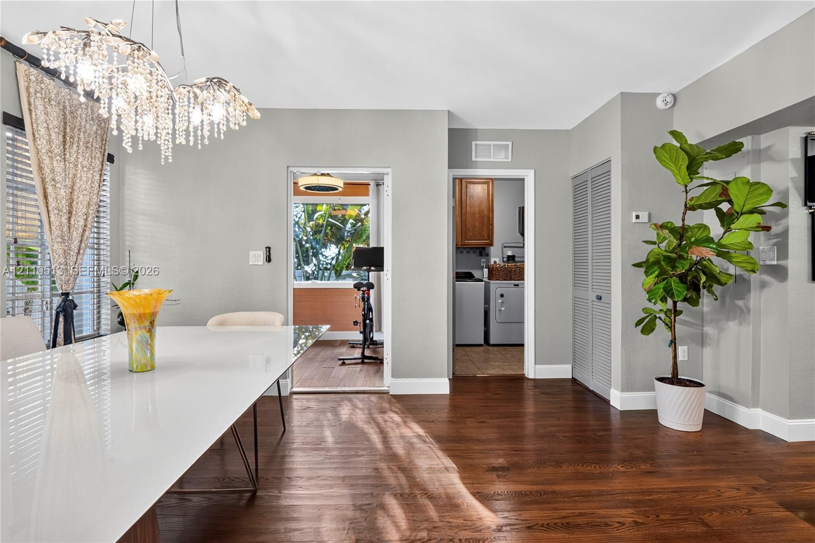 Wood-finish flooring, decorative crystal chandelier, and louvered closet doors