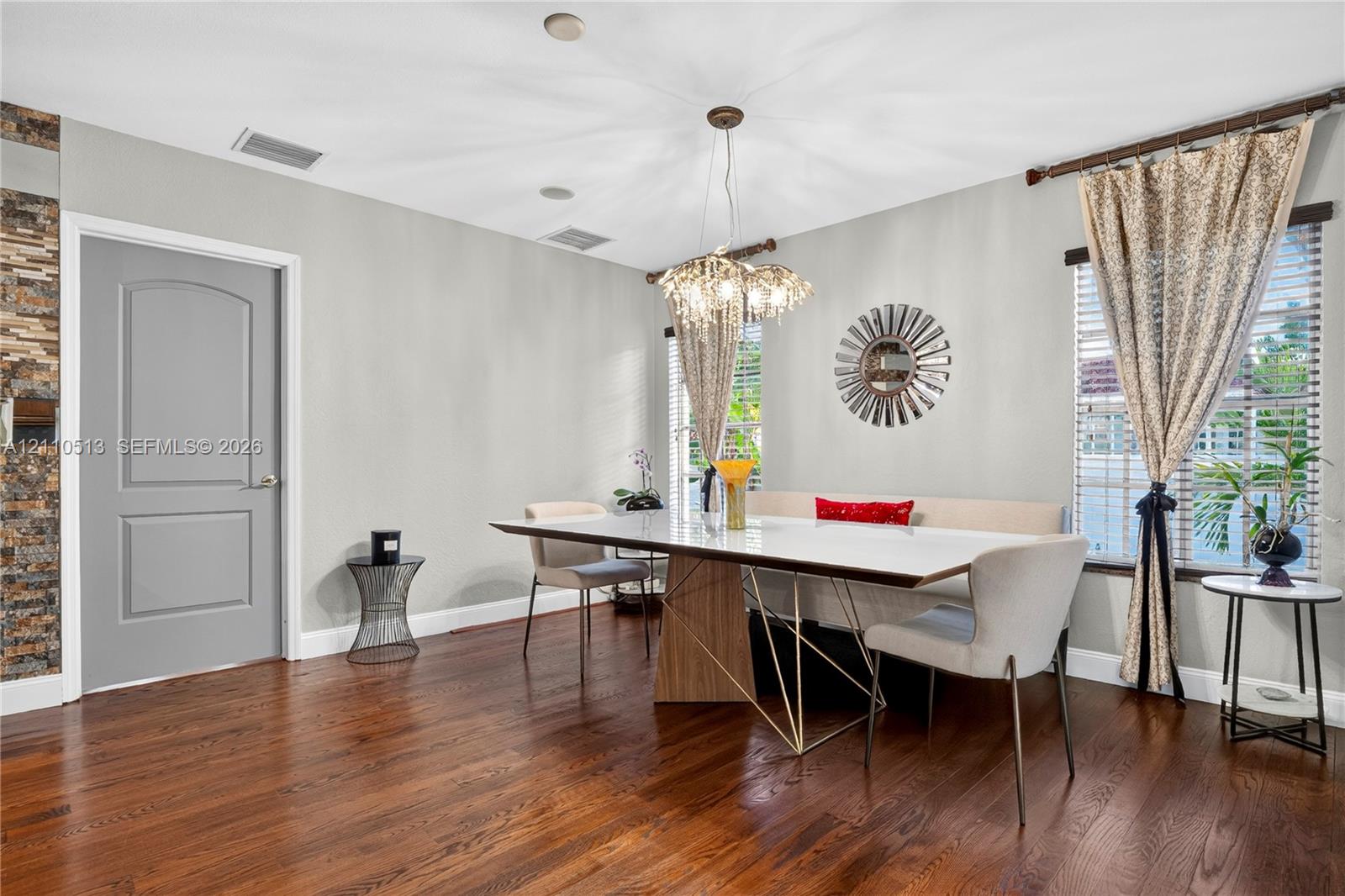Wood-finish flooring, multi-faceted crystal pendant lighting, stacked-stone accent wall, and arch-top door